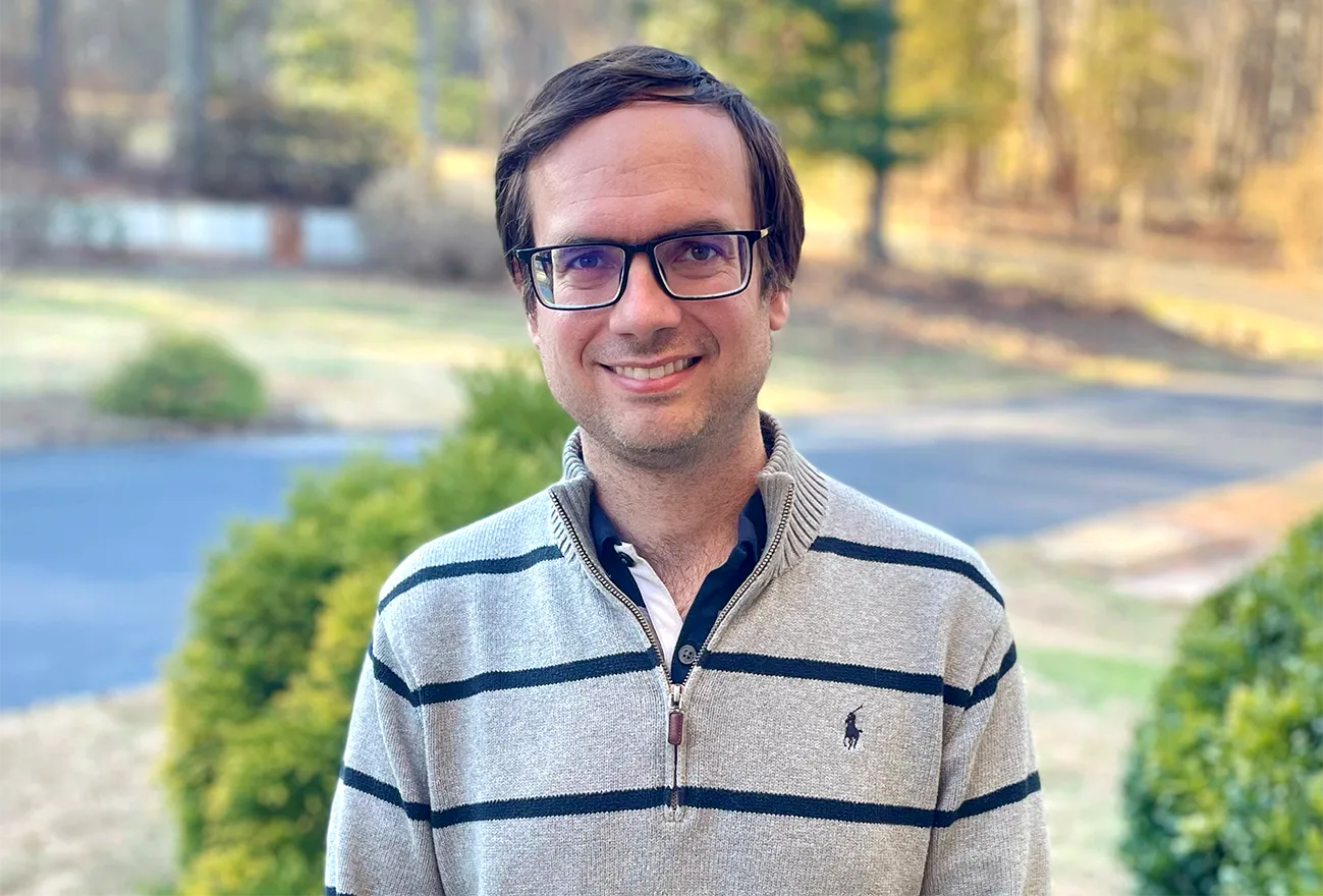 A smiling man in a striped polo shirt