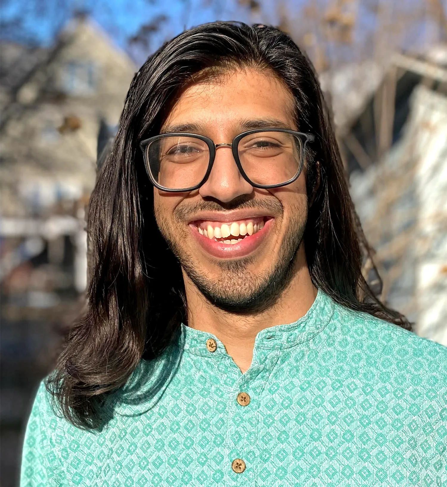 Portrait of a smily young man with long brown hair standing outside