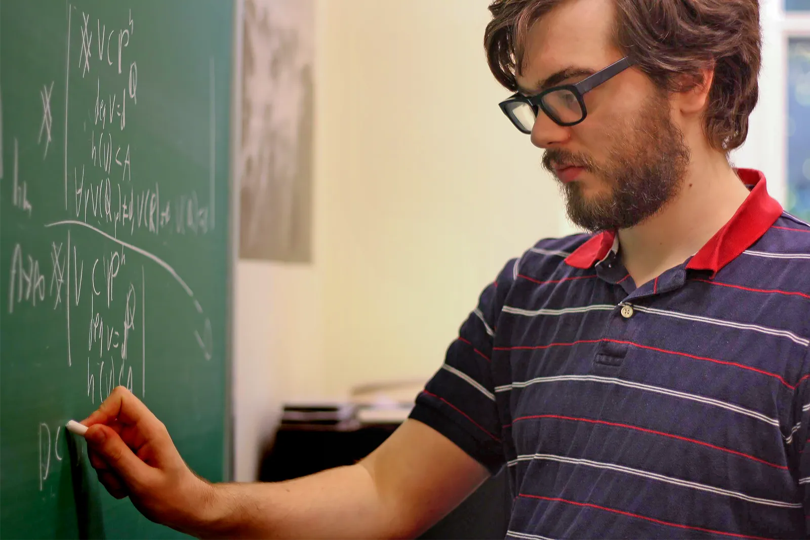 Professor Will Sawin of Columbia University writes equations on a blackboard.