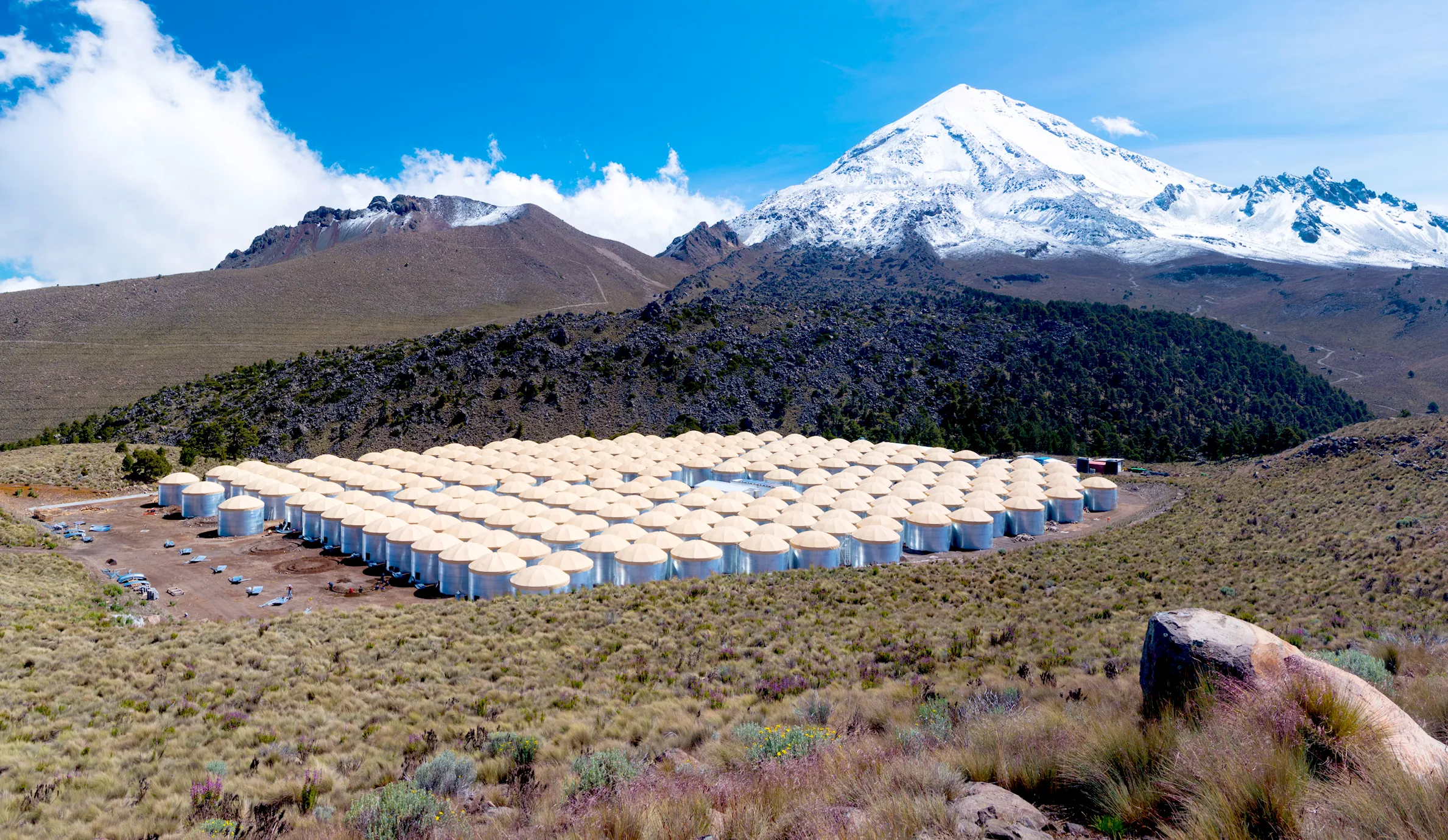 Photograph of hundreds of water-filled tanks at the base of a volcano, which make up the High-Altitude Water Cherenkov (HAWC) Gamma-Ray Observatory.