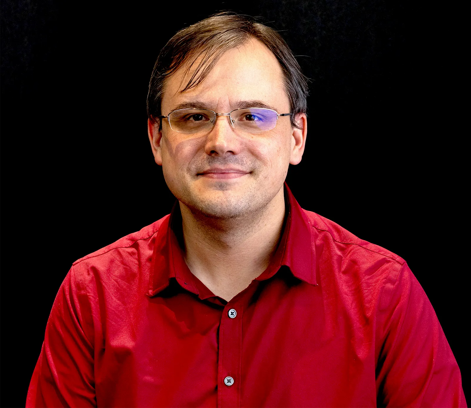 Jason Rute in a red shirt in front of a black background