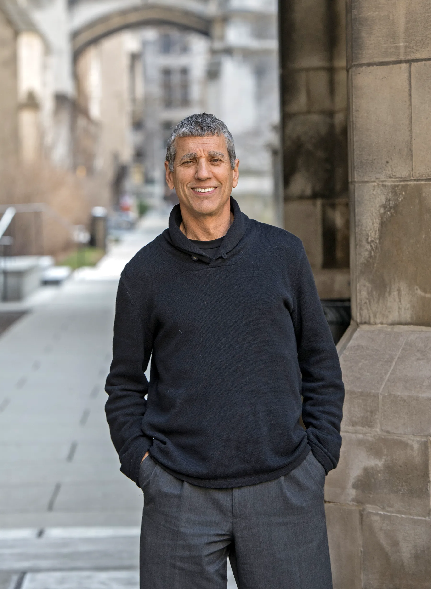 The researcher John Cacioppo standing in a long gallery of stone arches.