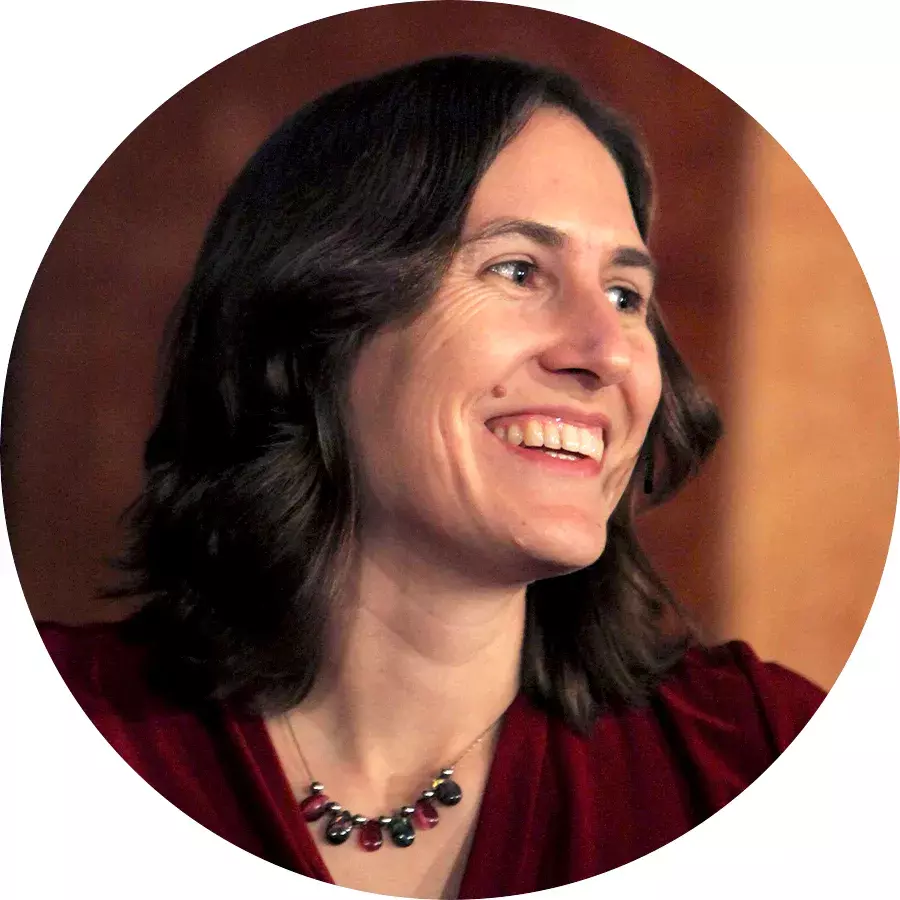 smiling light-skinned woman with shoulder-length, dark brown hair, and a dark red blouse