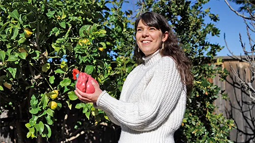 Researcher Kristy Red Horse holding a model of a human heart, with a lemon tree behind her.