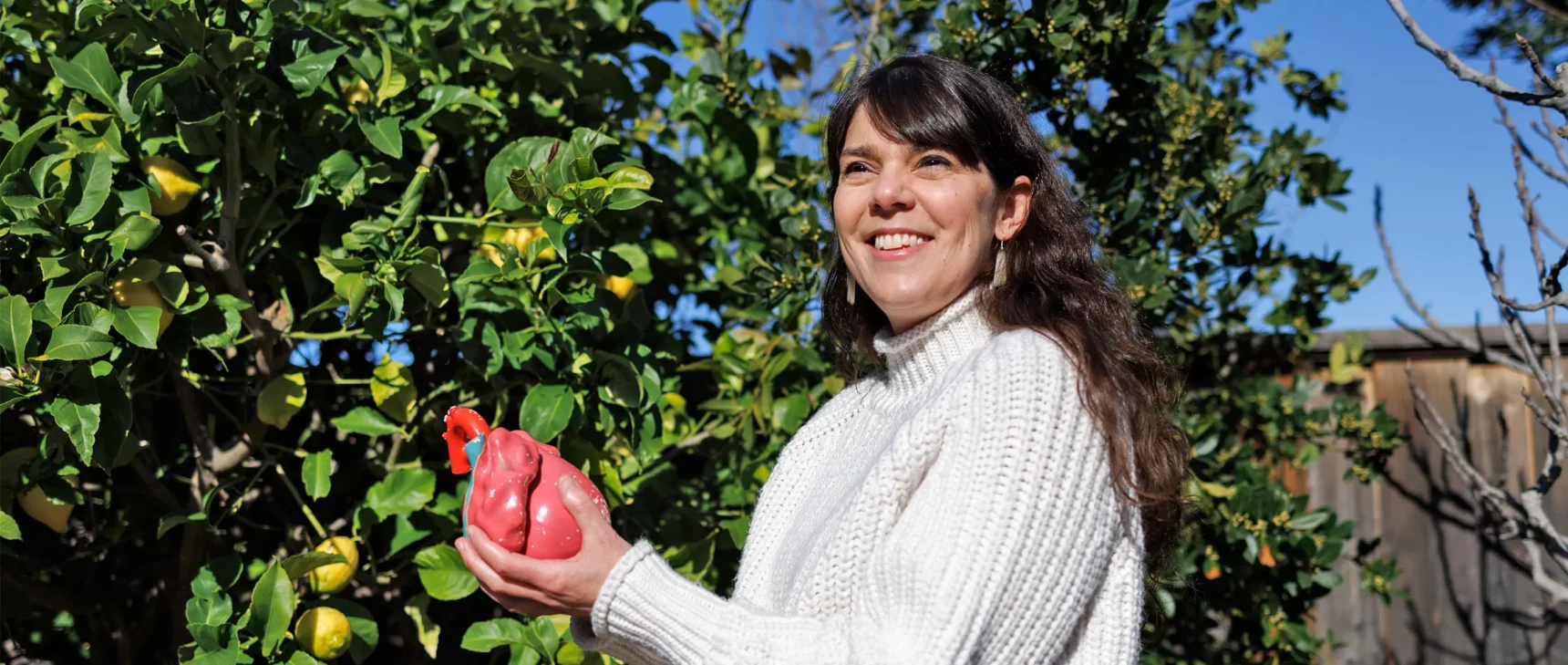 Researcher Kristy Red Horse holding a model of a human heart, with a lemon tree behind her.