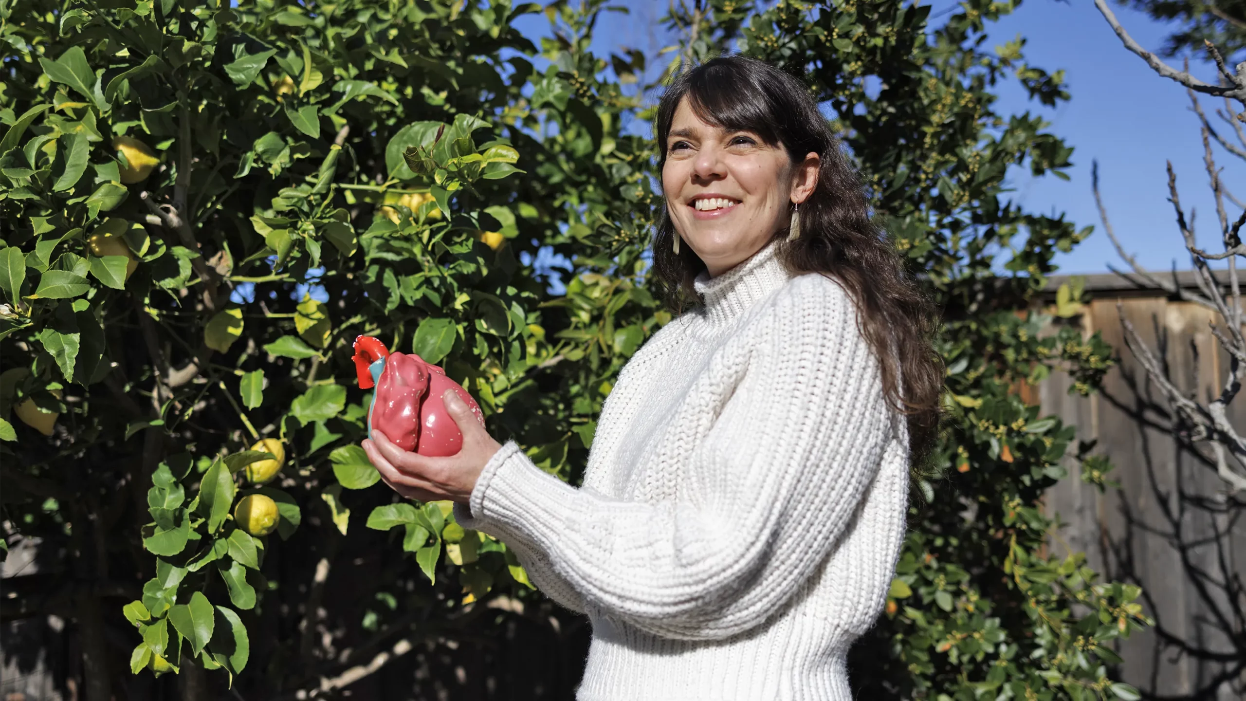 Researcher Kristy Red Horse holding a model of a human heart, with a lemon tree behind her.