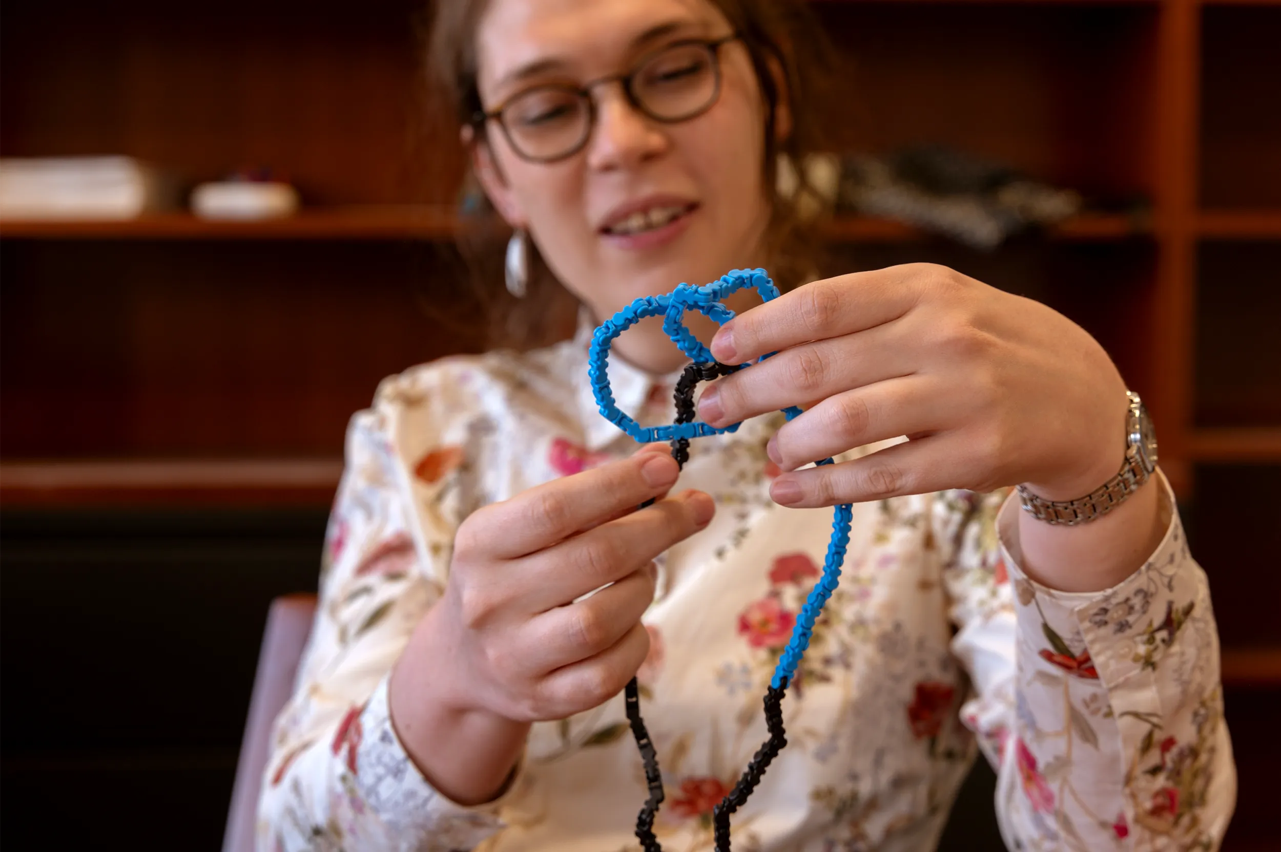 Emmy Murphy holding a blue and black Legendrian knot in her office at Princeton University.