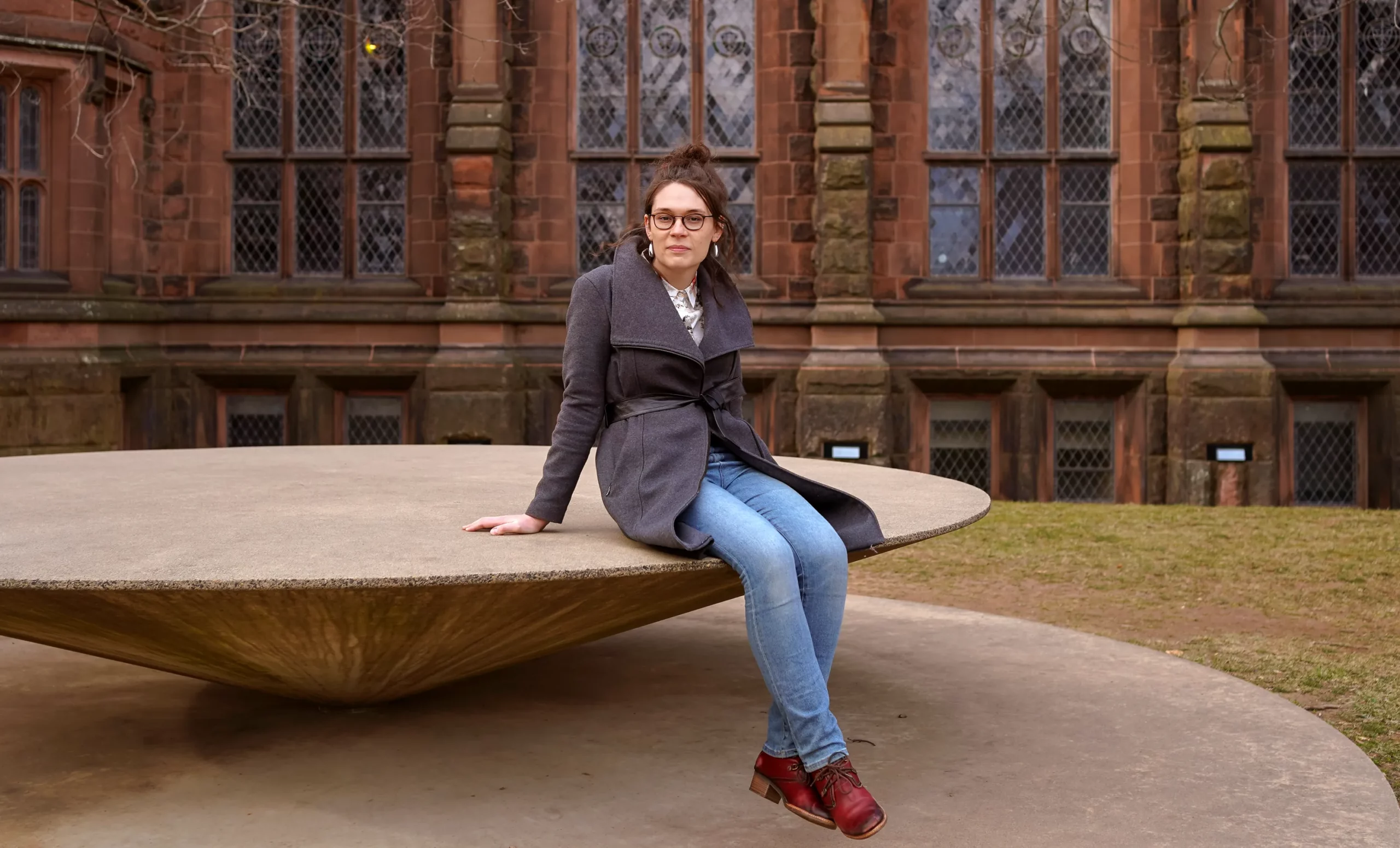 Emmy Murphy sitting on a large circular sculpture on the Princeton University campus.