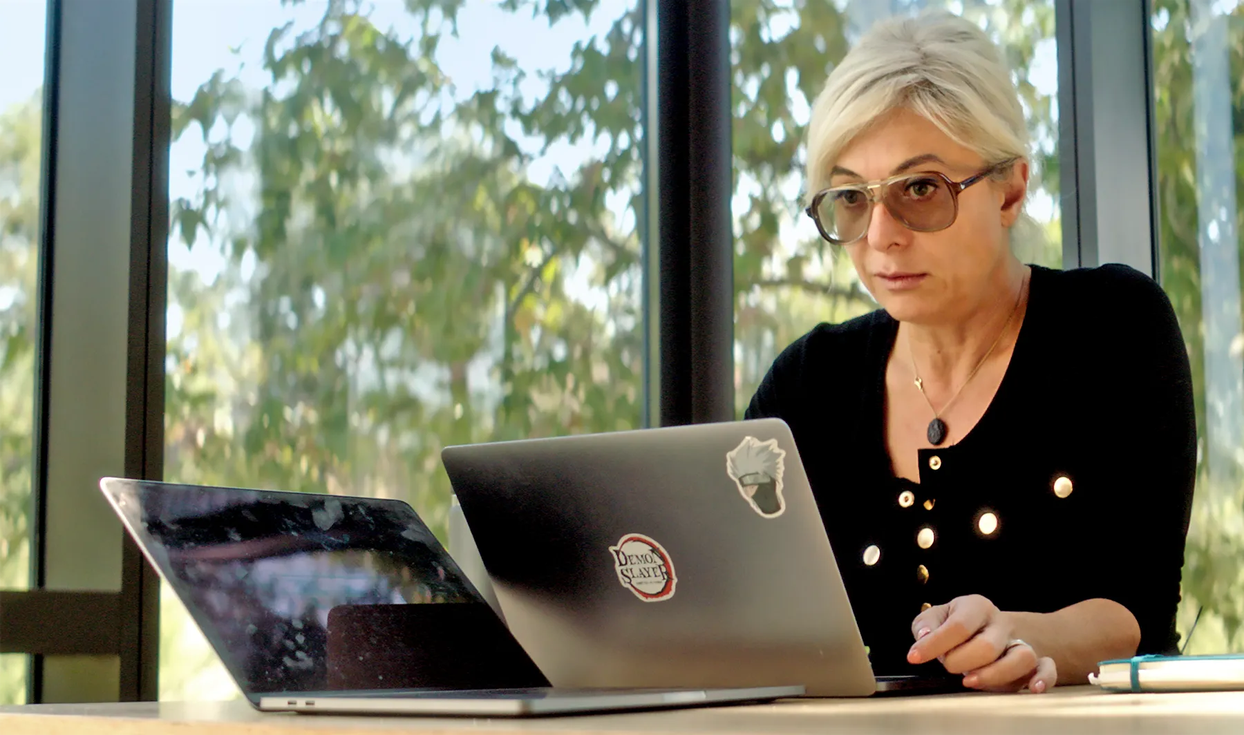 A blonde woman with glasses in front of a laptop.