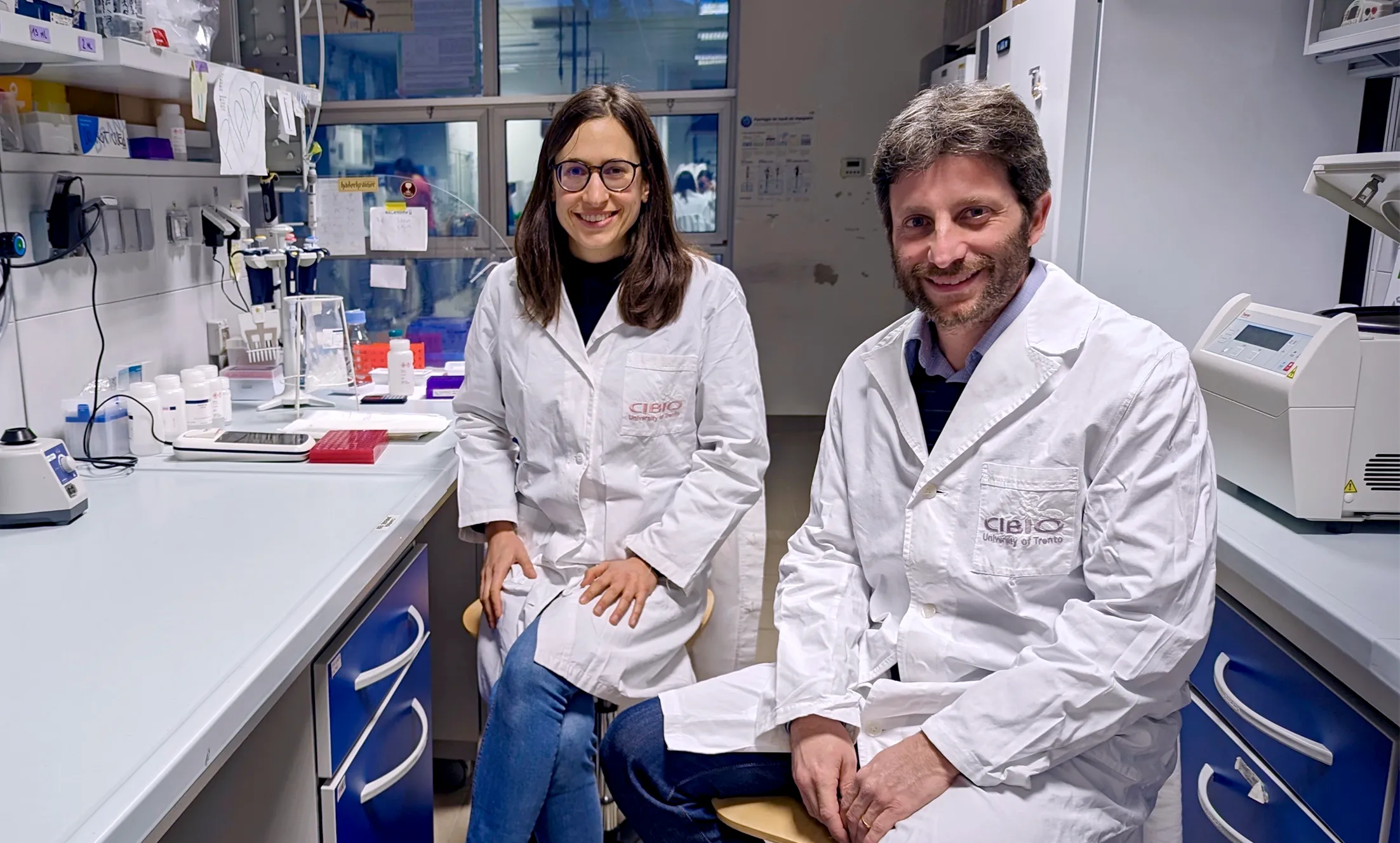 The researchers Mireia Valles-Colomer and Nicola Segata wearing lab coats and seated in their laboratory at the University of Trento in Italy.