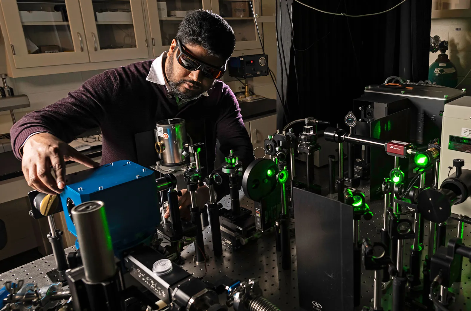 : Photograph of man standing in front of scientific equipment in a laboratory.