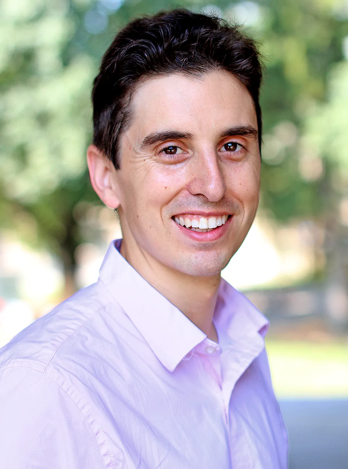 A smiling man in a pink shirt.