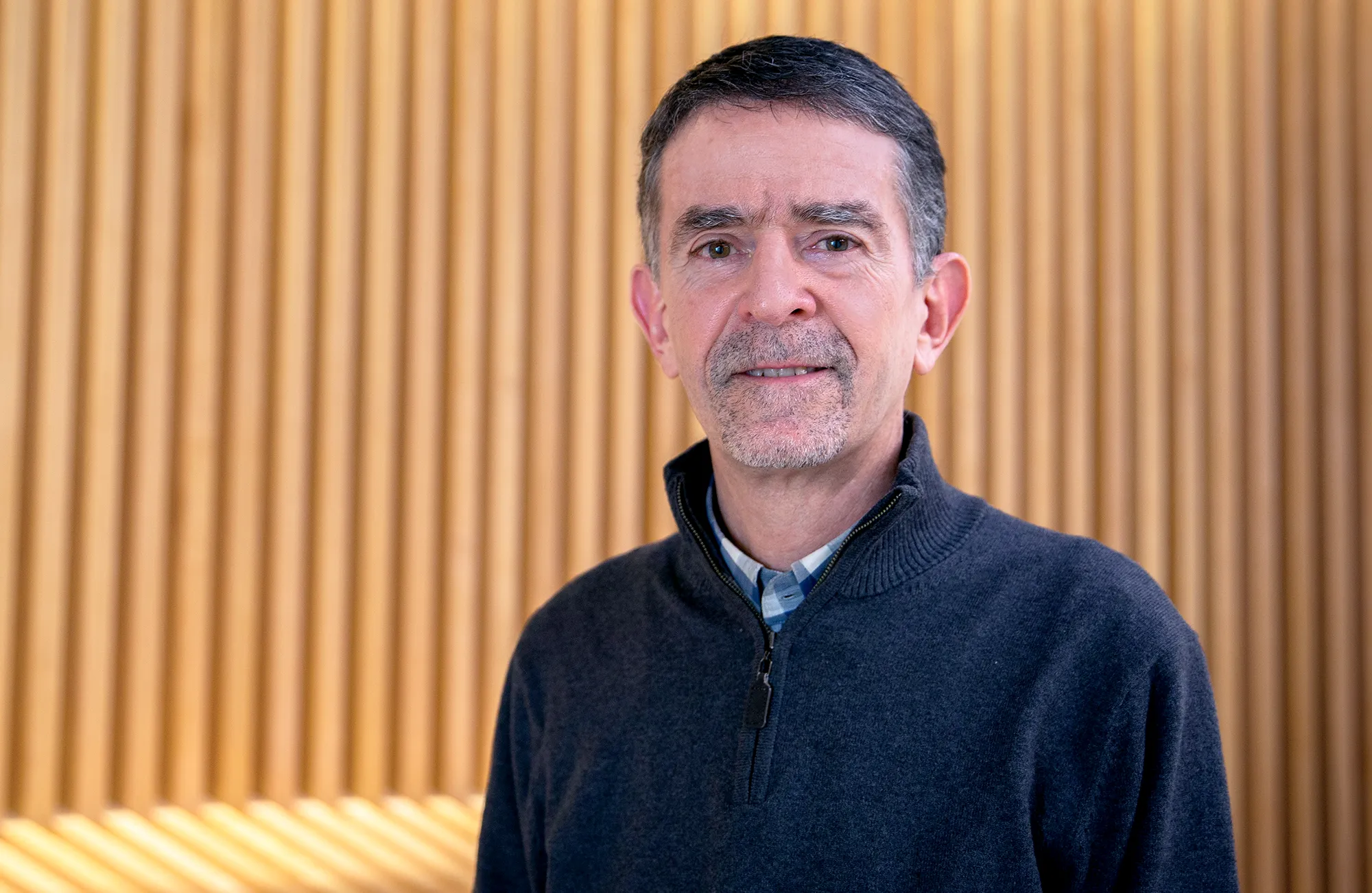 A man in front of a tan background.