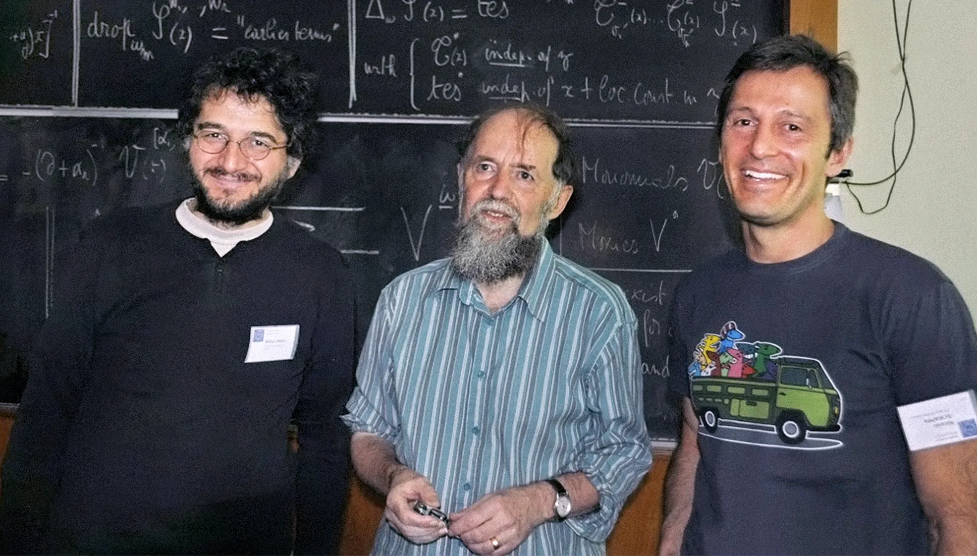 three men in front of a chalk board.