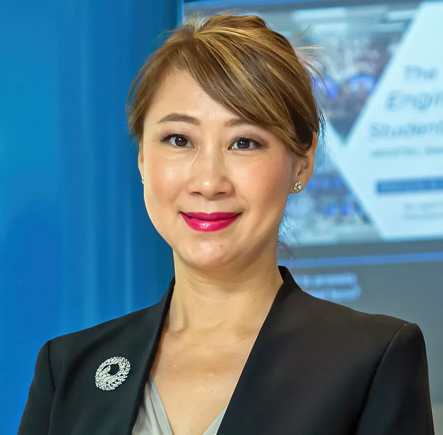 Pascale Fung in a blazer stands next to a blue wall with her university logo.