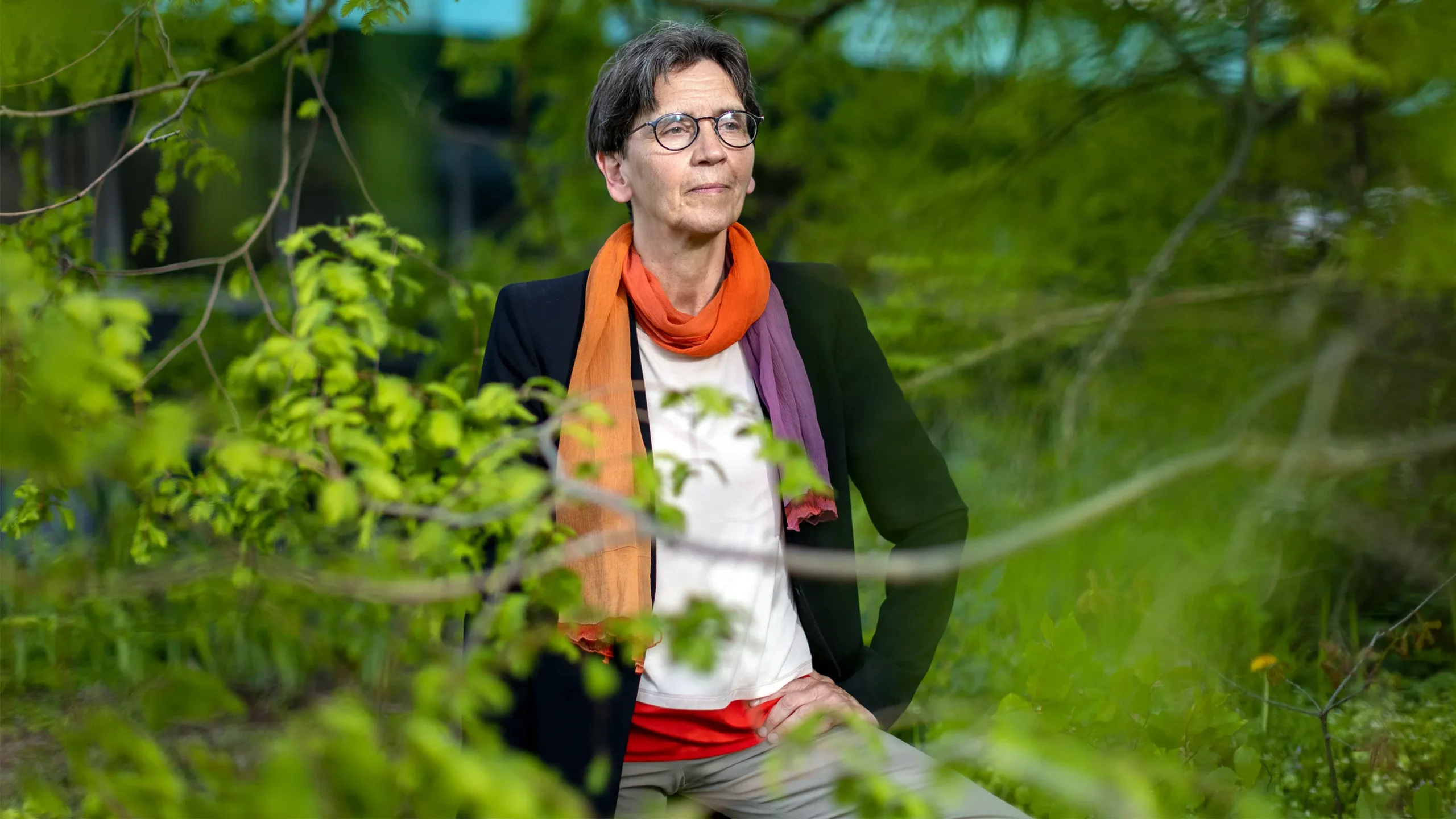 Renate Loll, a theoretical physicist, looking thoughtful amid trees and bright green grasses.