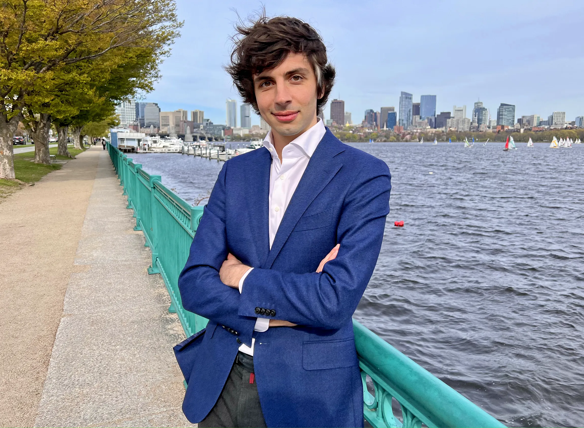 A man wearing a blue blazer stands by a river.