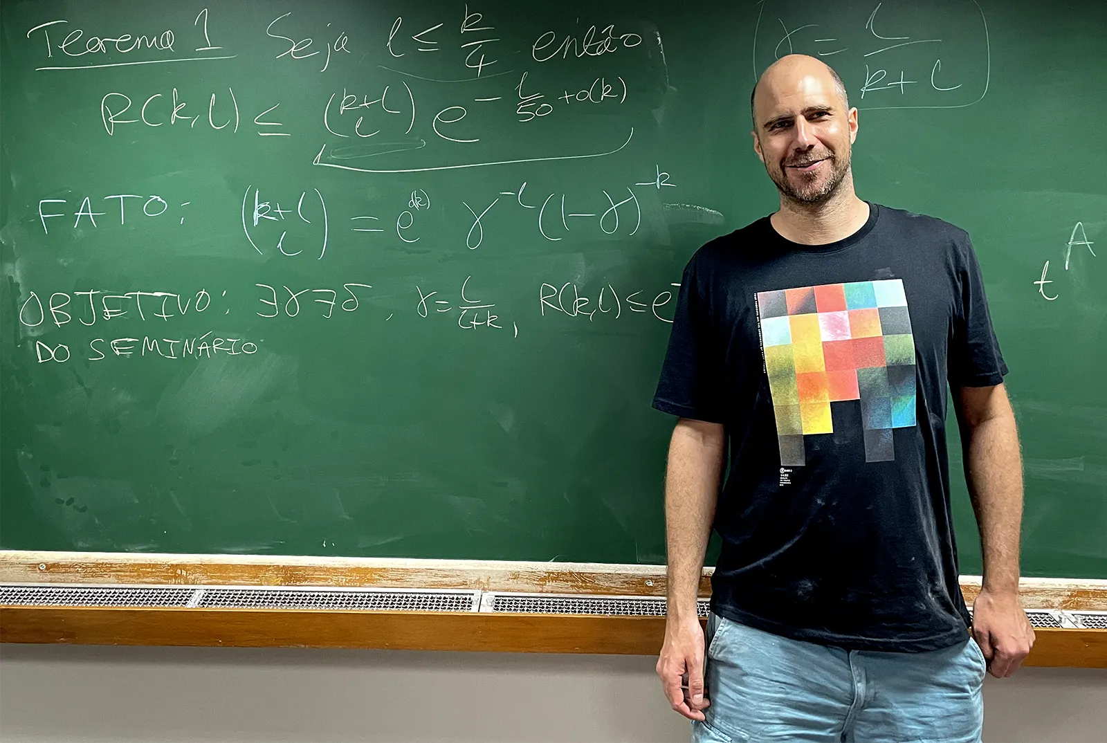 Simon Griffiths in front of a chalkboard covered with equations.