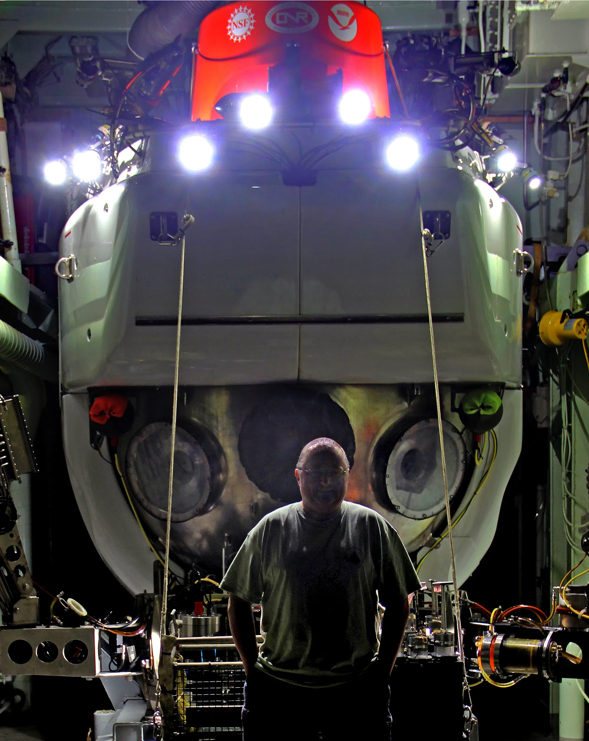 German stands in silhouette by the bow of the Alvin submersible.