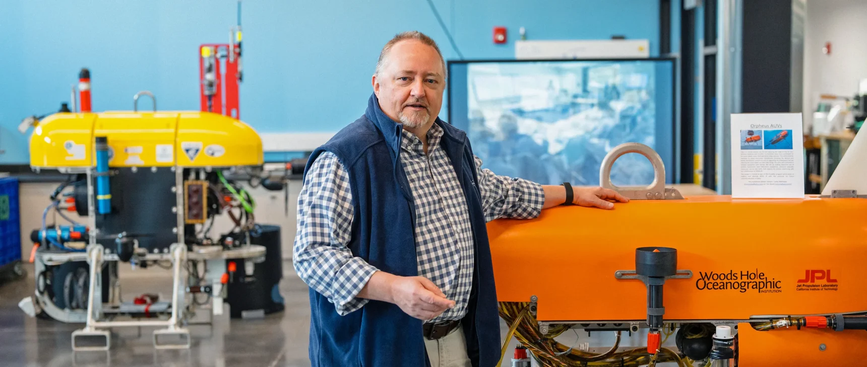 Researcher Chris German standing beside a remotely operated vehicle at the Woods Hole Oceanographic Institute.