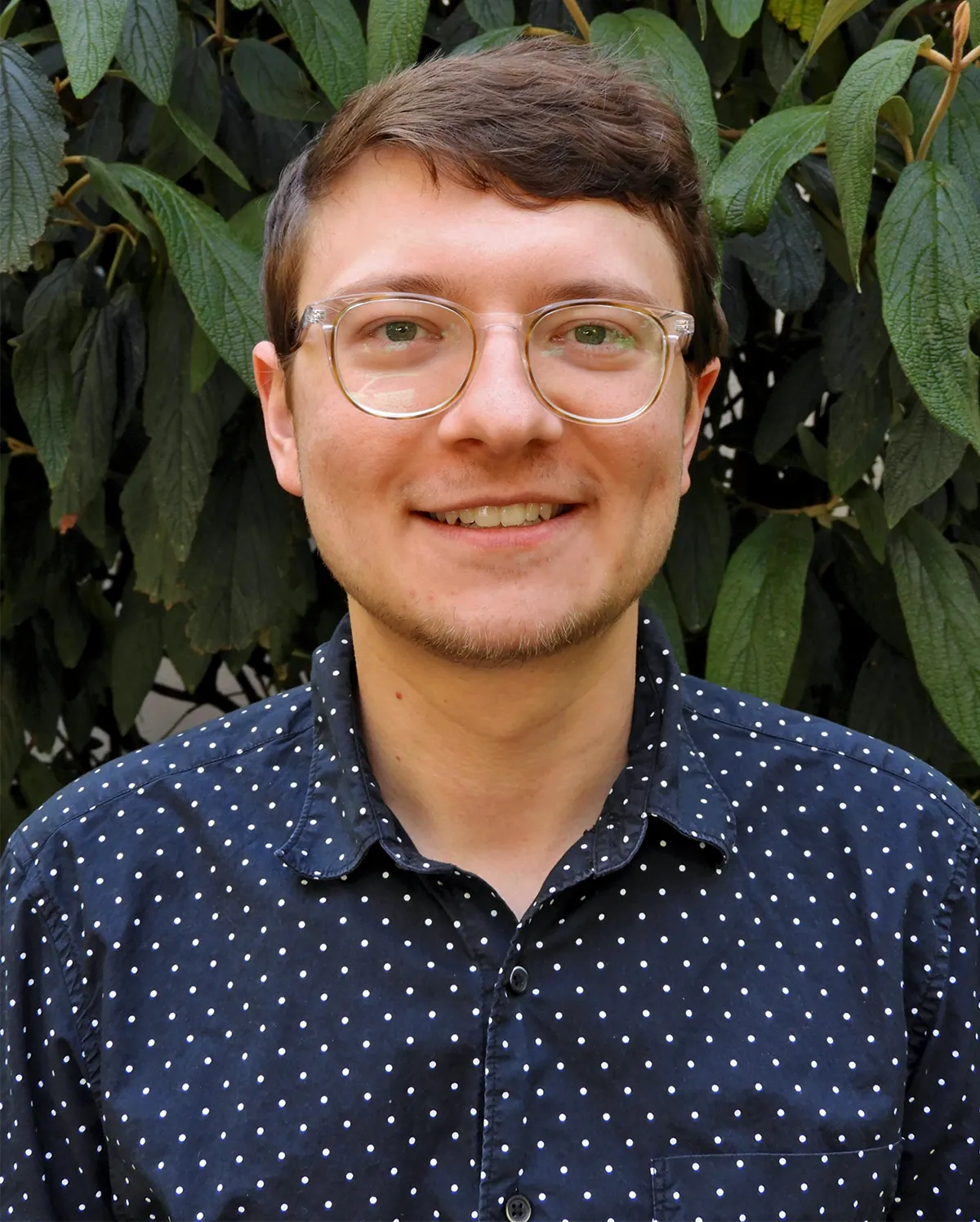 Kenneth Jops standing in front of greenery.