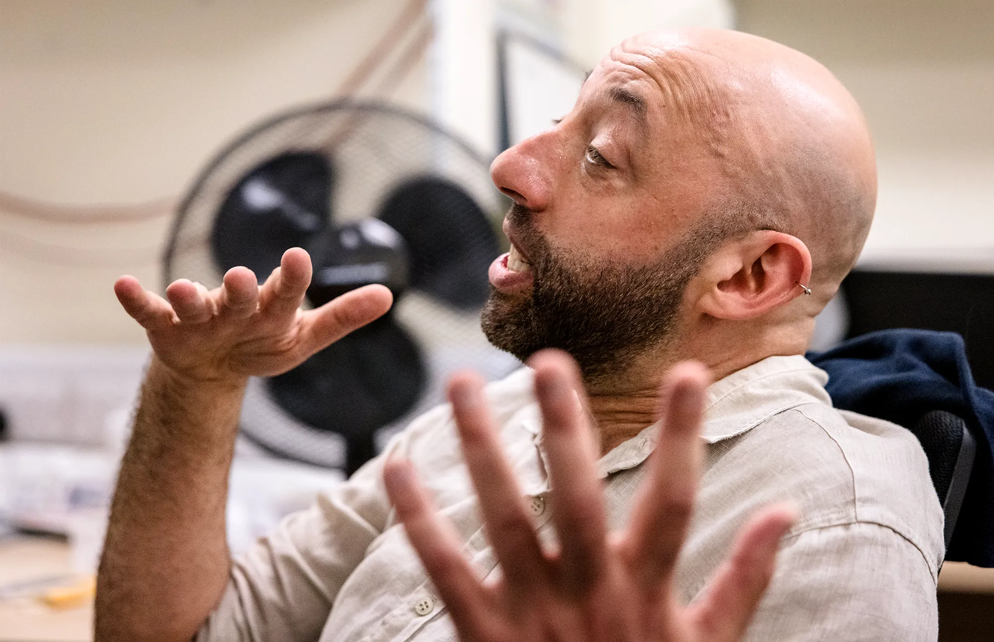 A portrait of Oppenheim in profile. He is mid-sentence and gesturing with his hands.