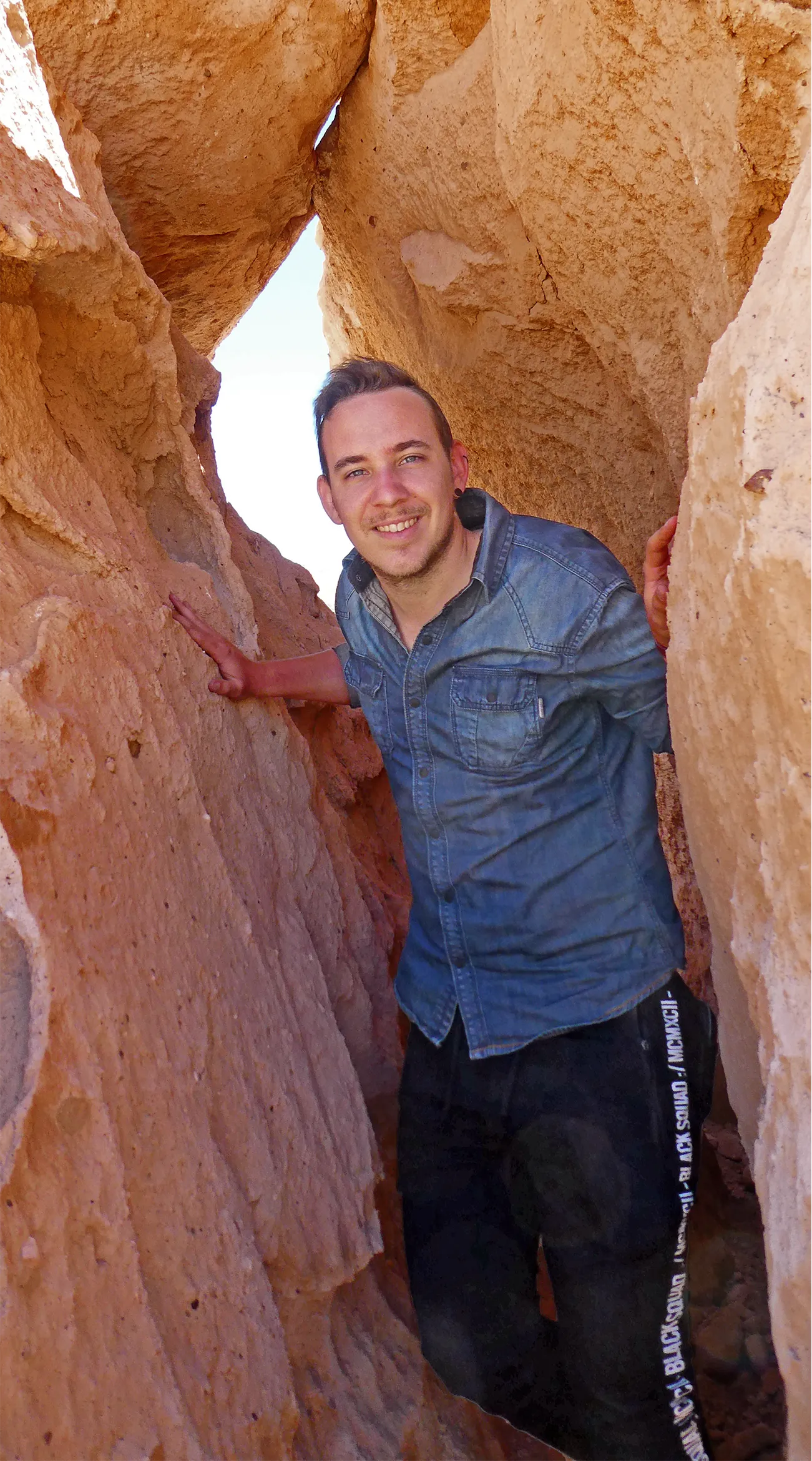 Patrick Jung standing inside a desert rock formation sculpted by weathering.