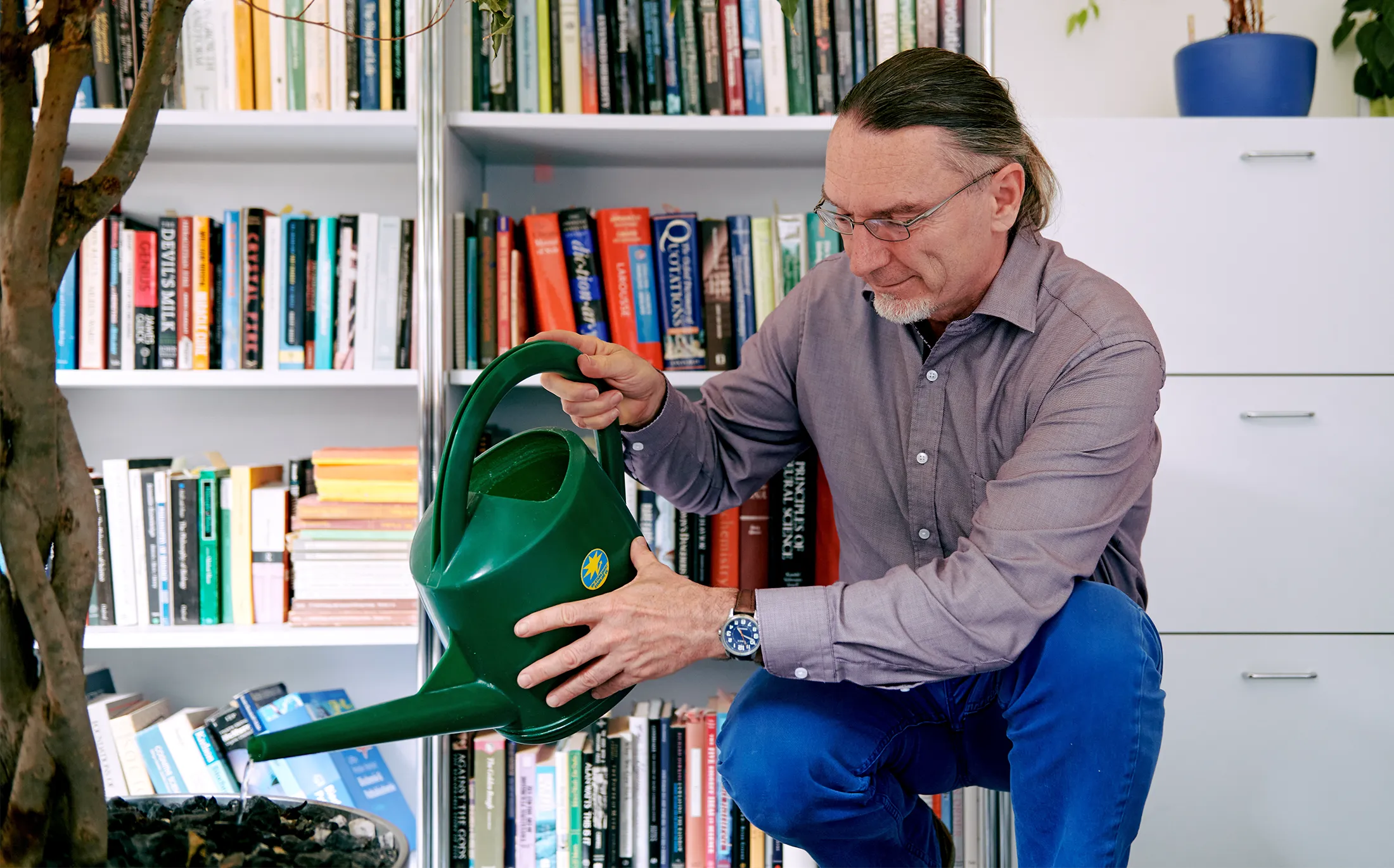 Andreas Wagner waters a large potted plant on the floor of his office at the University of Zurich.