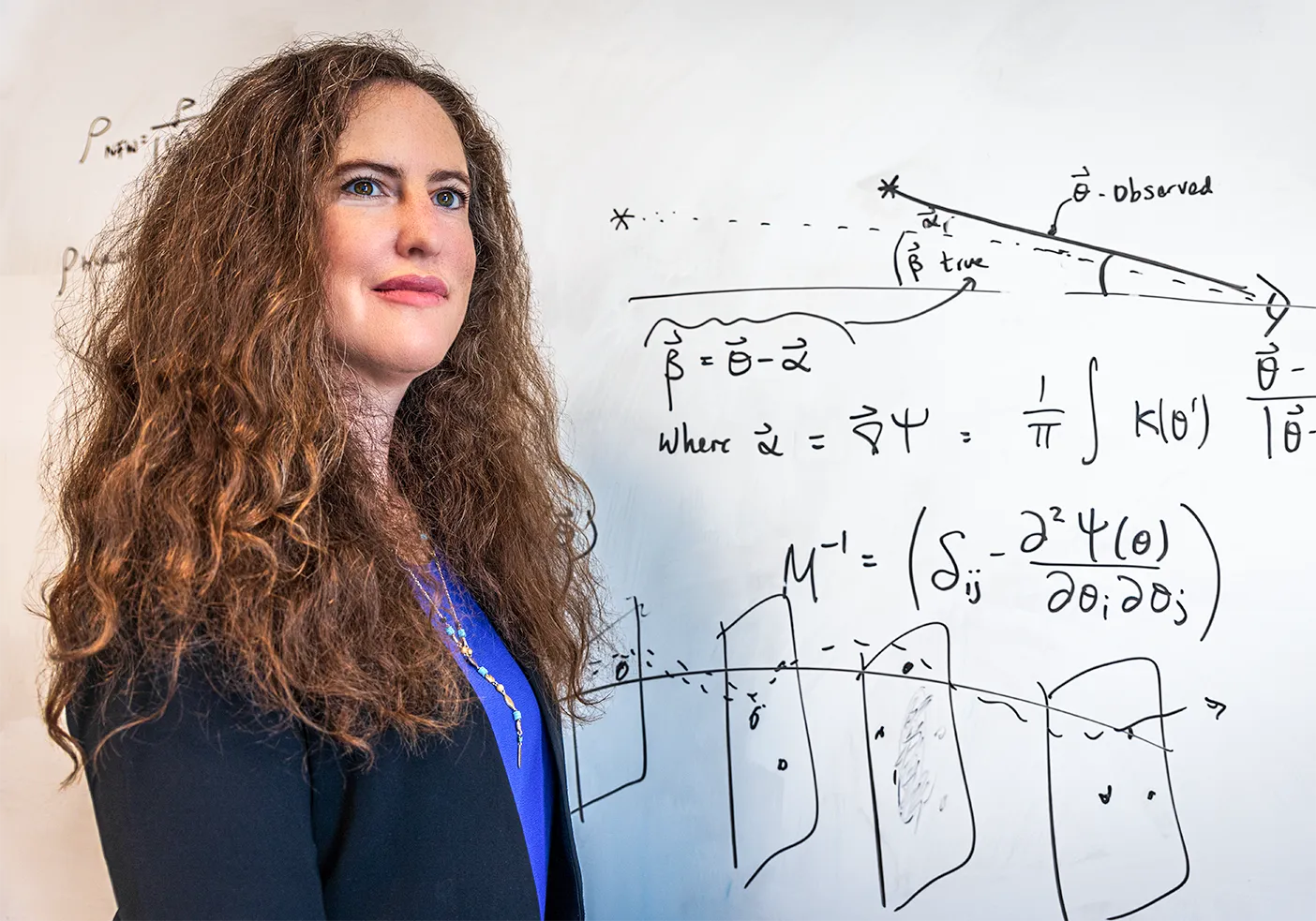 Anna Nierenberg standing in front of a white board, which is filled with diagrams and equations.