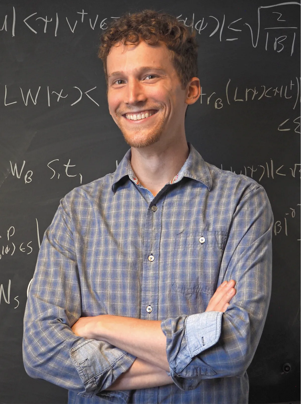 A man stands before a black board.