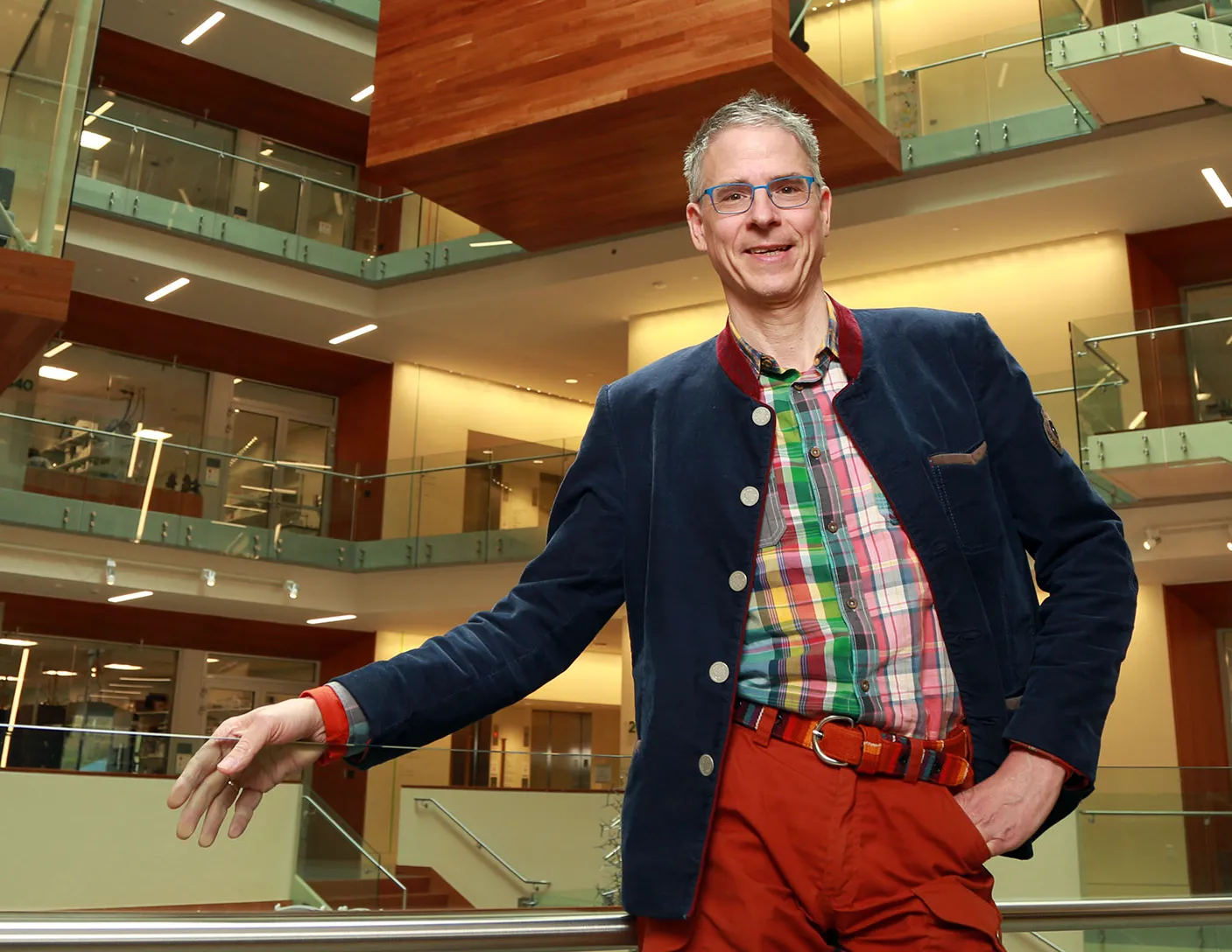 The neuroscientist Christof Koch standing in the atrium of the Allen Institute for Brain Science headquarters, with the stairs leading up to different floors behind him.