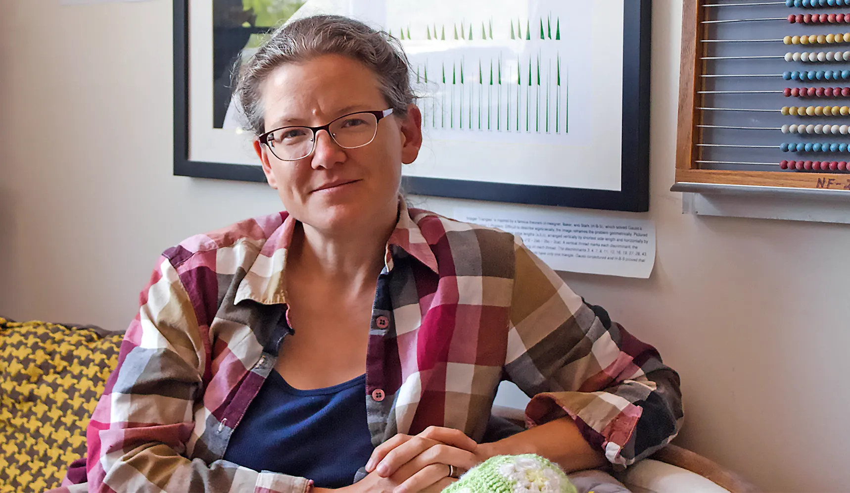 A woman in glasses sitting on a couch.