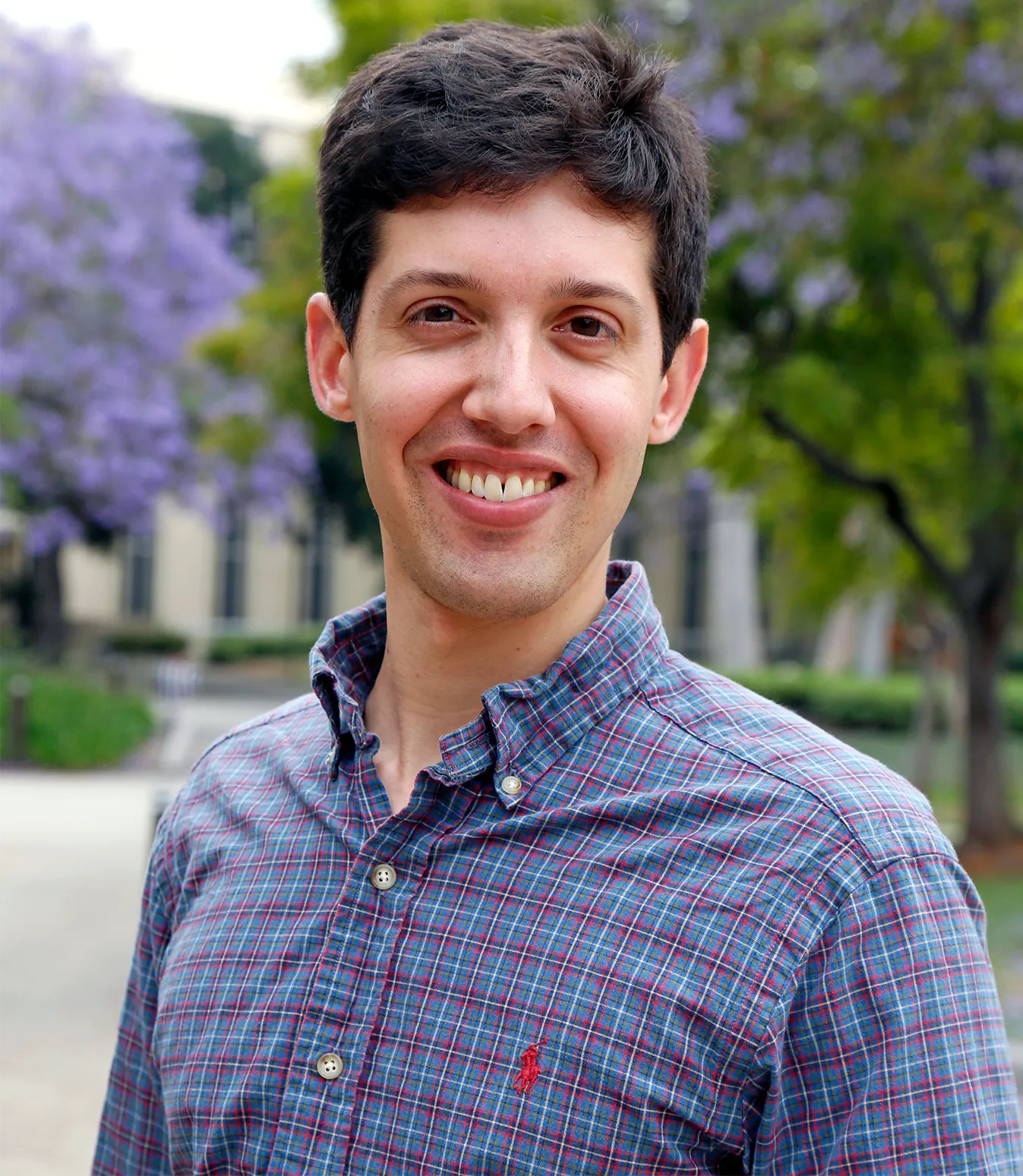 A portrait of Minnich smiling at the camera, with flowering trees in the background.