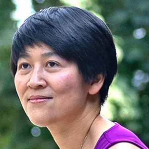 Cynthia Chiang on the McGill University campus. She is perched on a concrete wall, wearing a purple shirt and gray jeans, and the Montreal skyline is in the background.