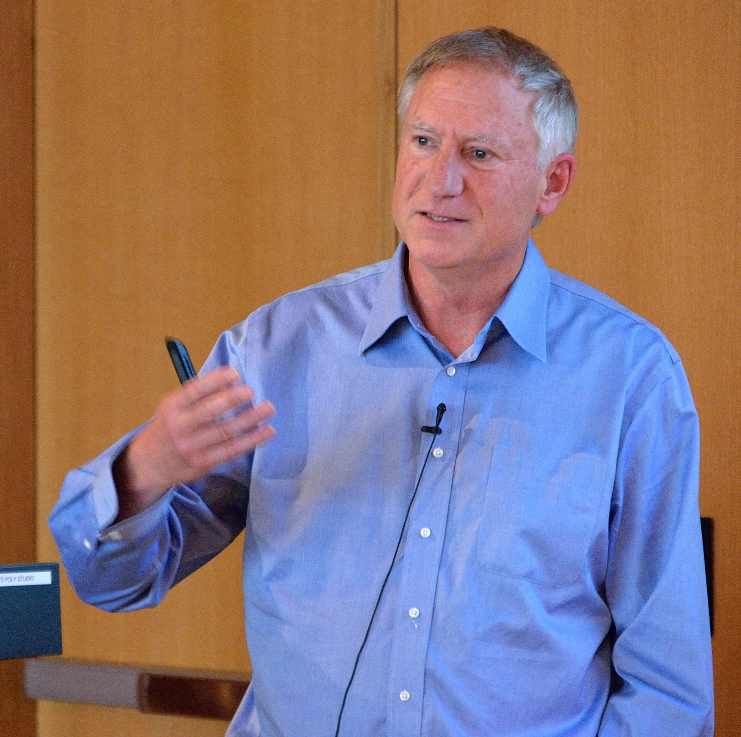 Matthew Fisher in a blue shirt giving a lecture.