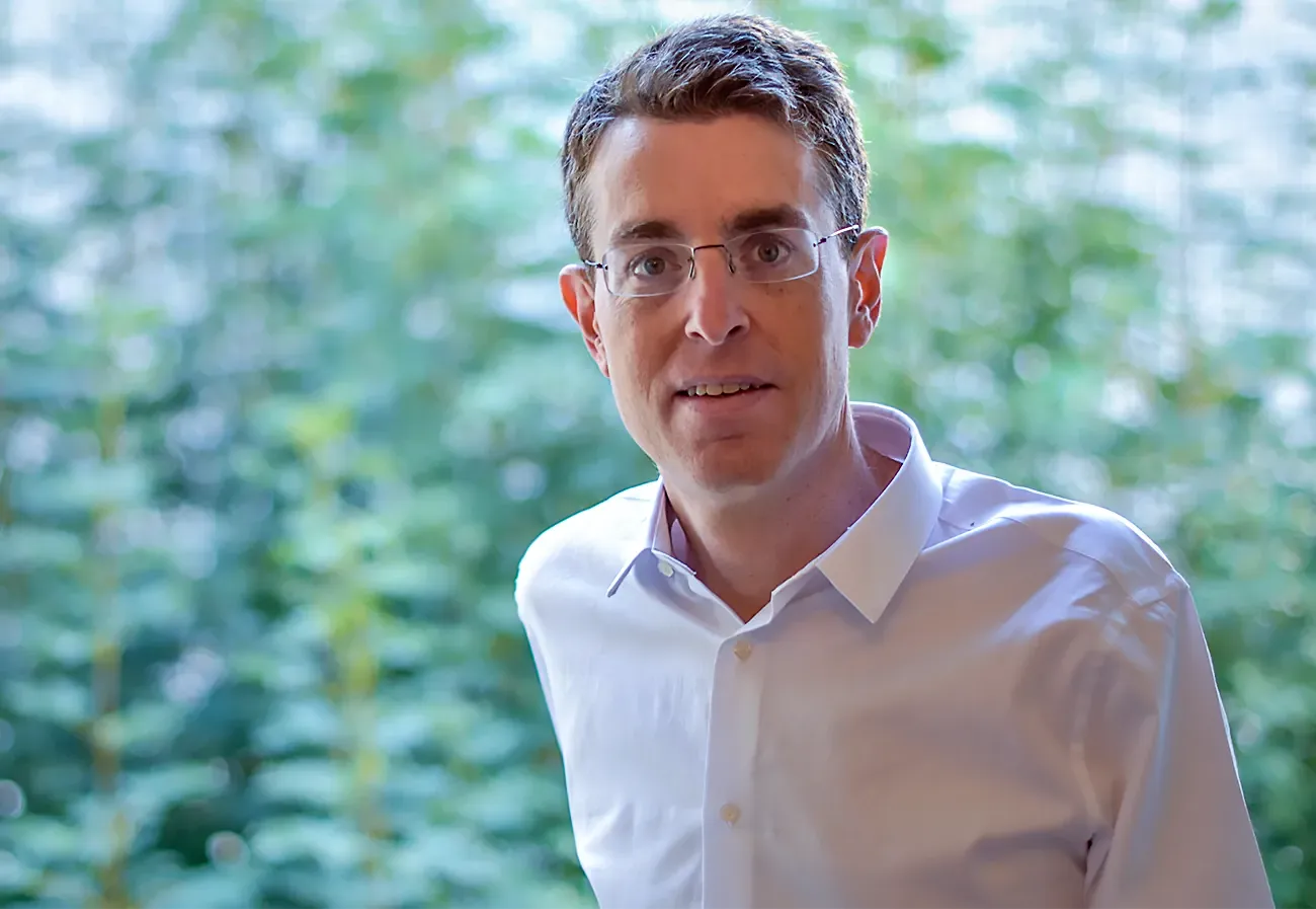 Oded Regev in a white shirt in front of a green background