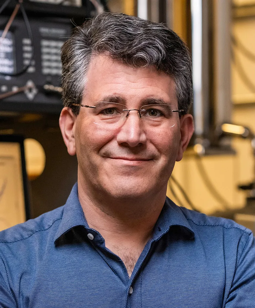 A portrait of Douglas Natelson wearing a blue shirt and smiling.