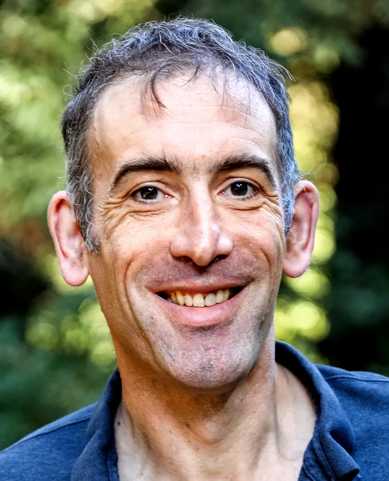 A portrait of Francis Nimmo smiling, with trees in the background.