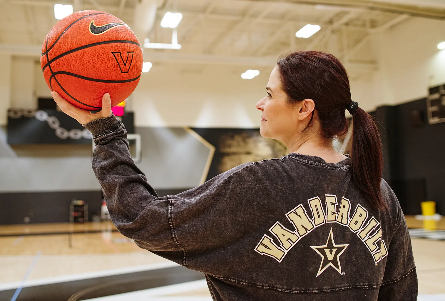 Erin Calipari holds a basketball while standing on a Vanderbilt basketball court.