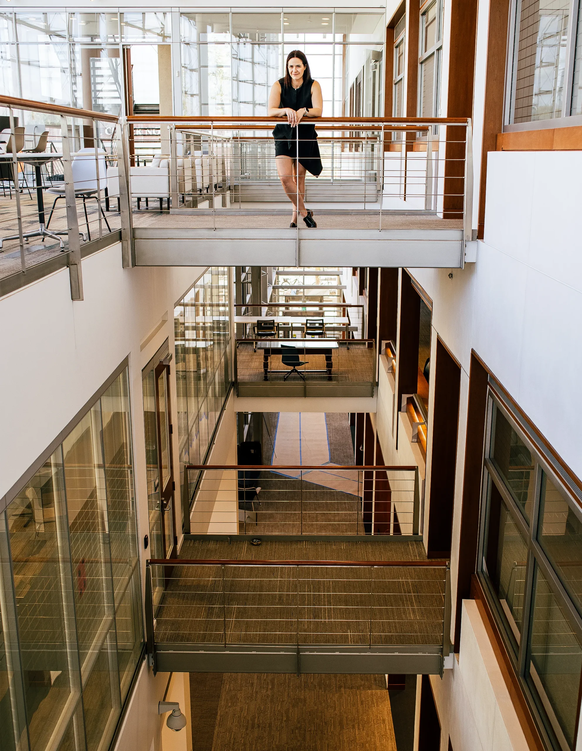 Calipari stands on a small bridge in a wide open corridor in her laboratory building.