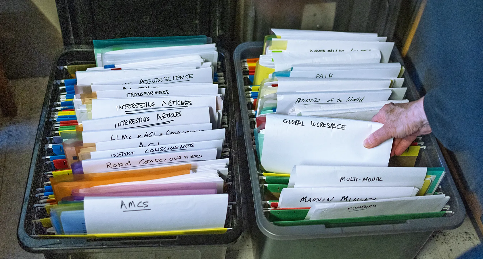 A hand grabs a stack of folders labeled “Global Workspace” amid many other folders