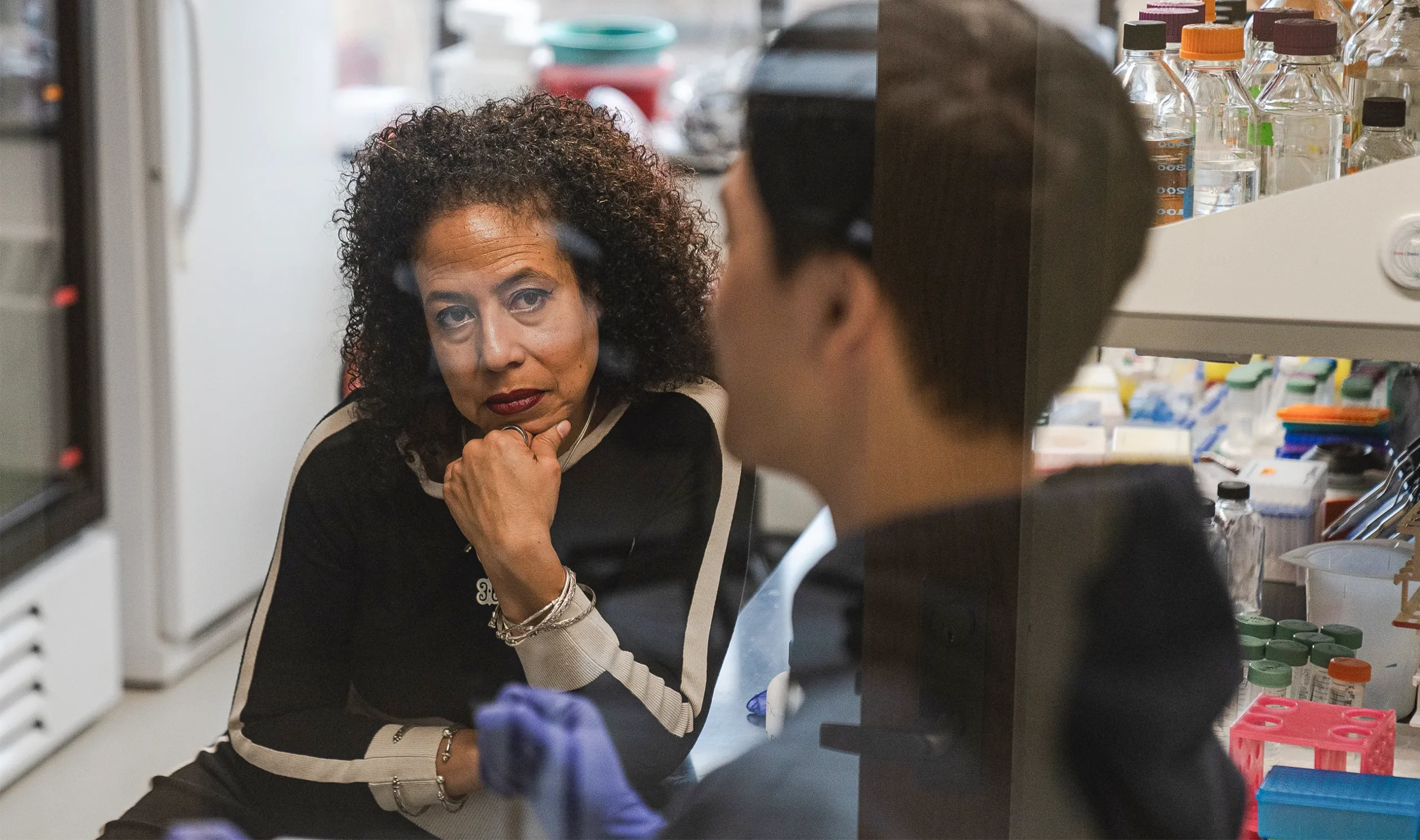 The researcher Cassandra Extavour, seated with her chin on her hand, in conversation with one of the graduate students in her laboratory at Harvard University.