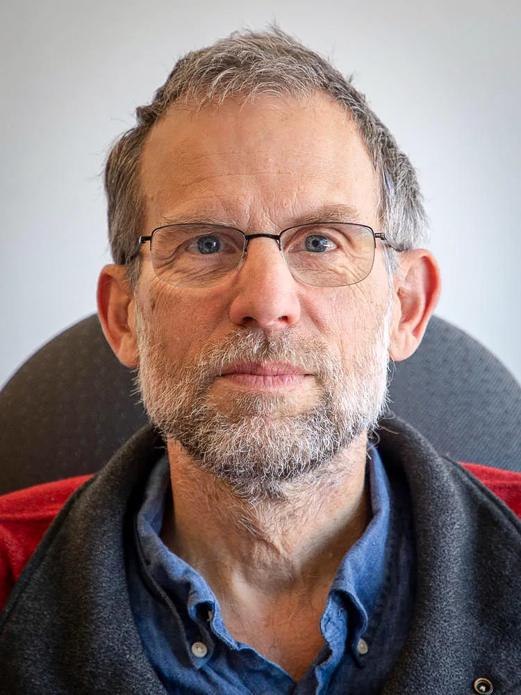 A man wearing glasses sits in an office chair.