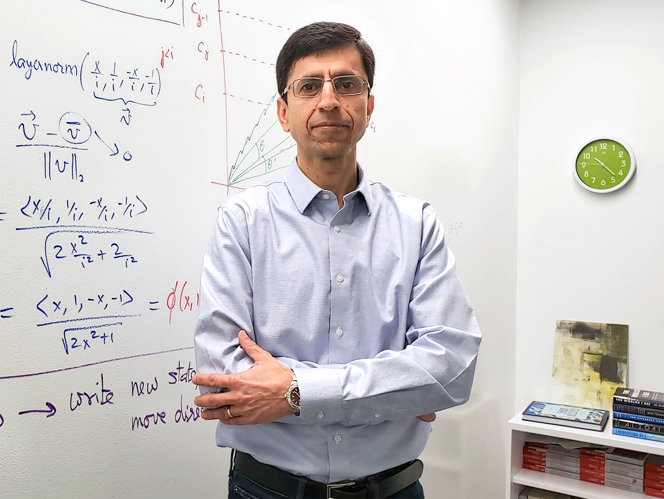 Ashish Sabharwal in a blue shirt stands in front of a filled white board and office furniture.