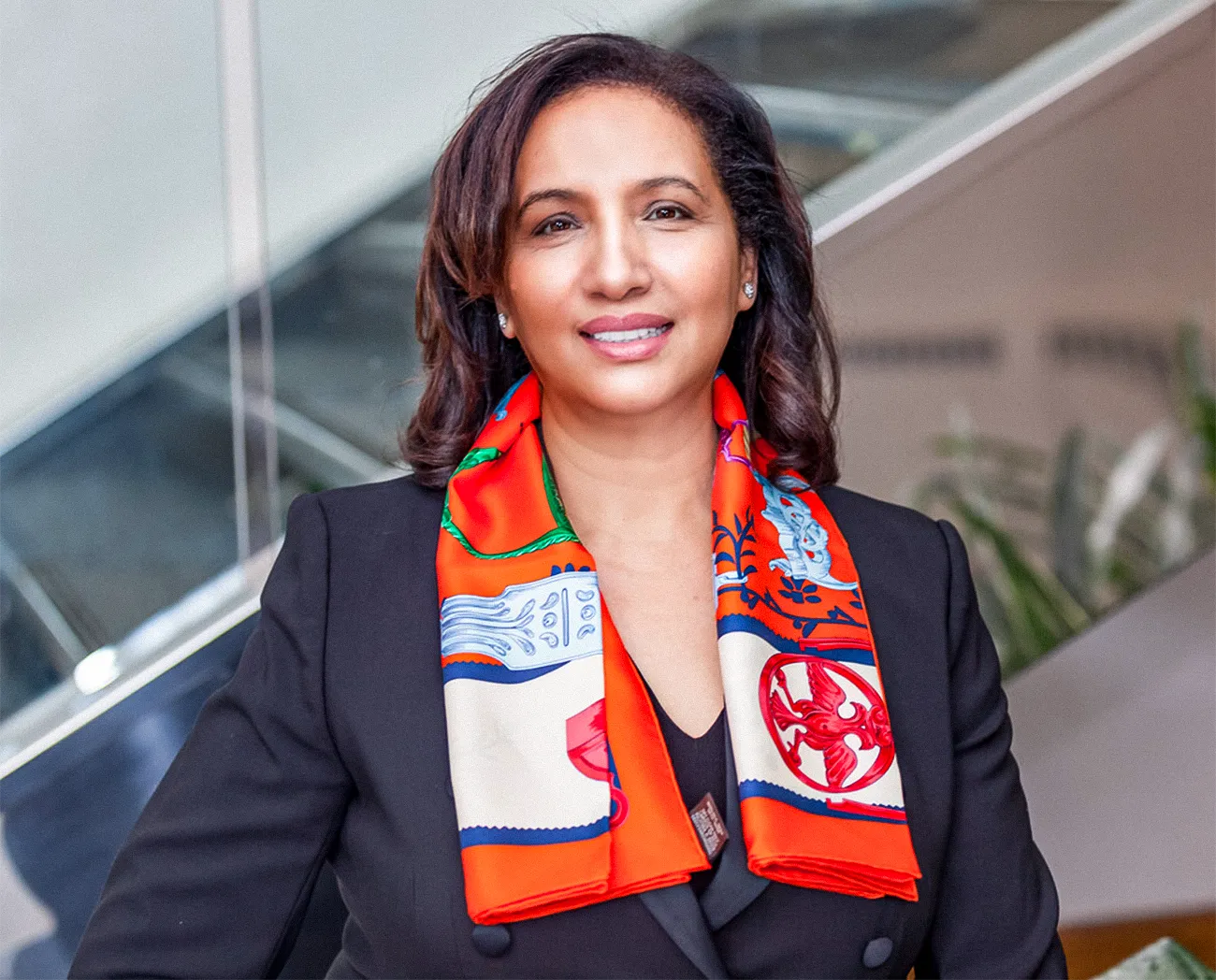 A woman in a bright orange scarf stands in front of a staircase.