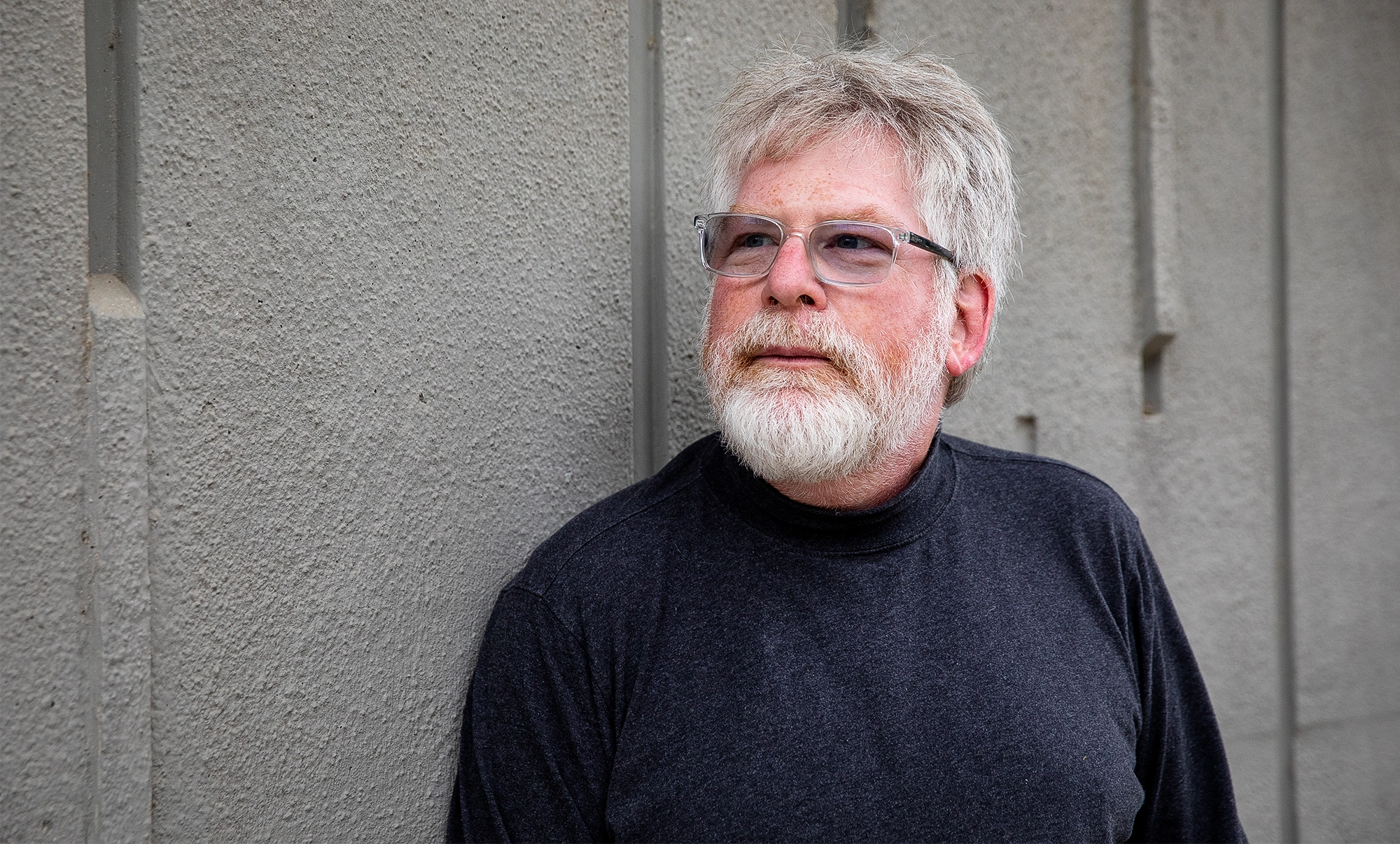 Russell Impagliazzo, in a dark shirt, gazes into the distance