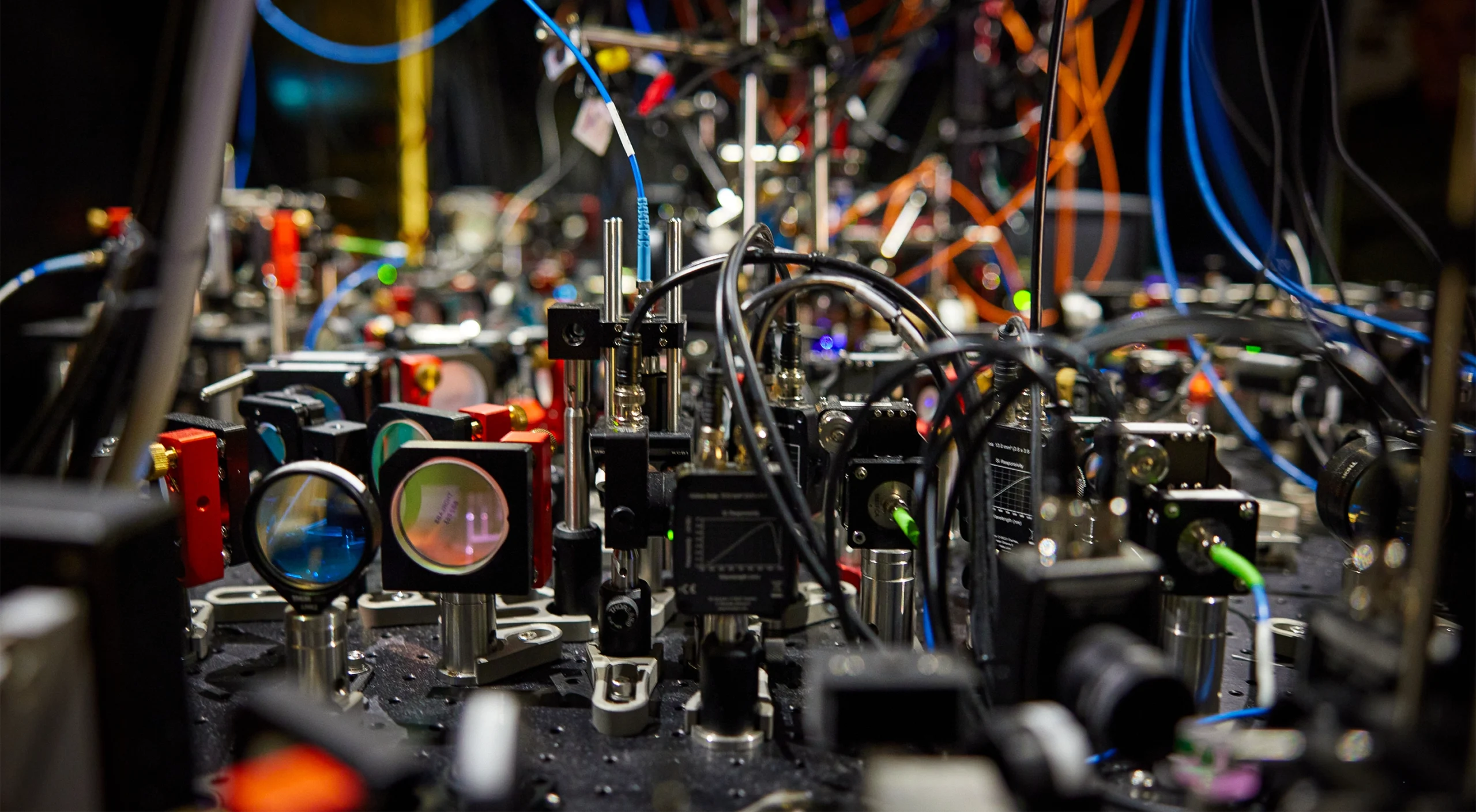 A close-up view of an optical table crammed with optical devices and electronics.