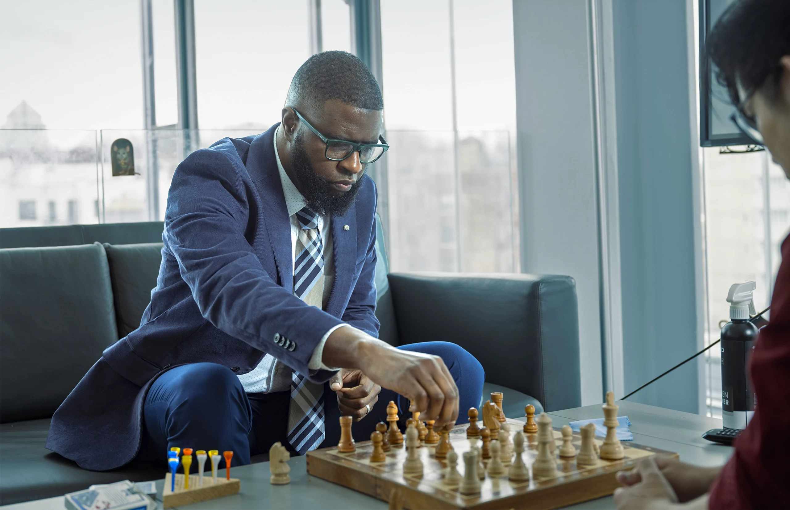 The neuroscientist Ishmail Abdus-Saboor, in jacket and tie, plays chess with his student Preston Shang while sitting on a sofa.