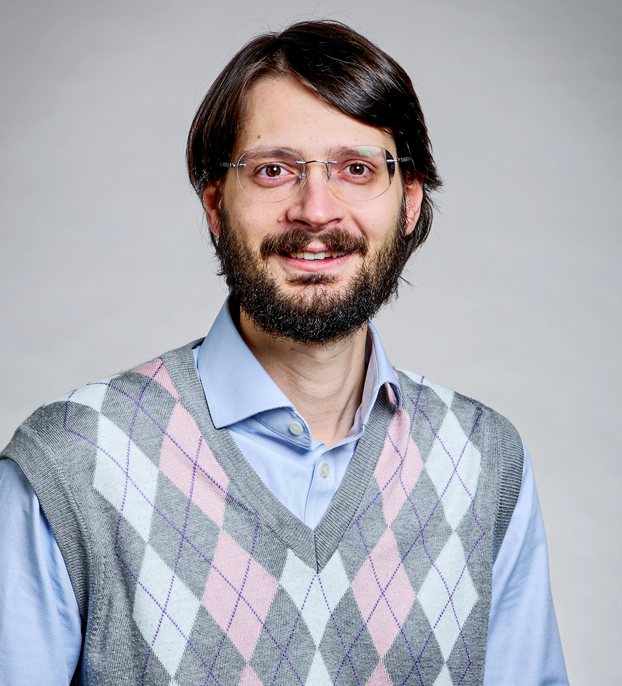 A bearded man wears a checkered vest.