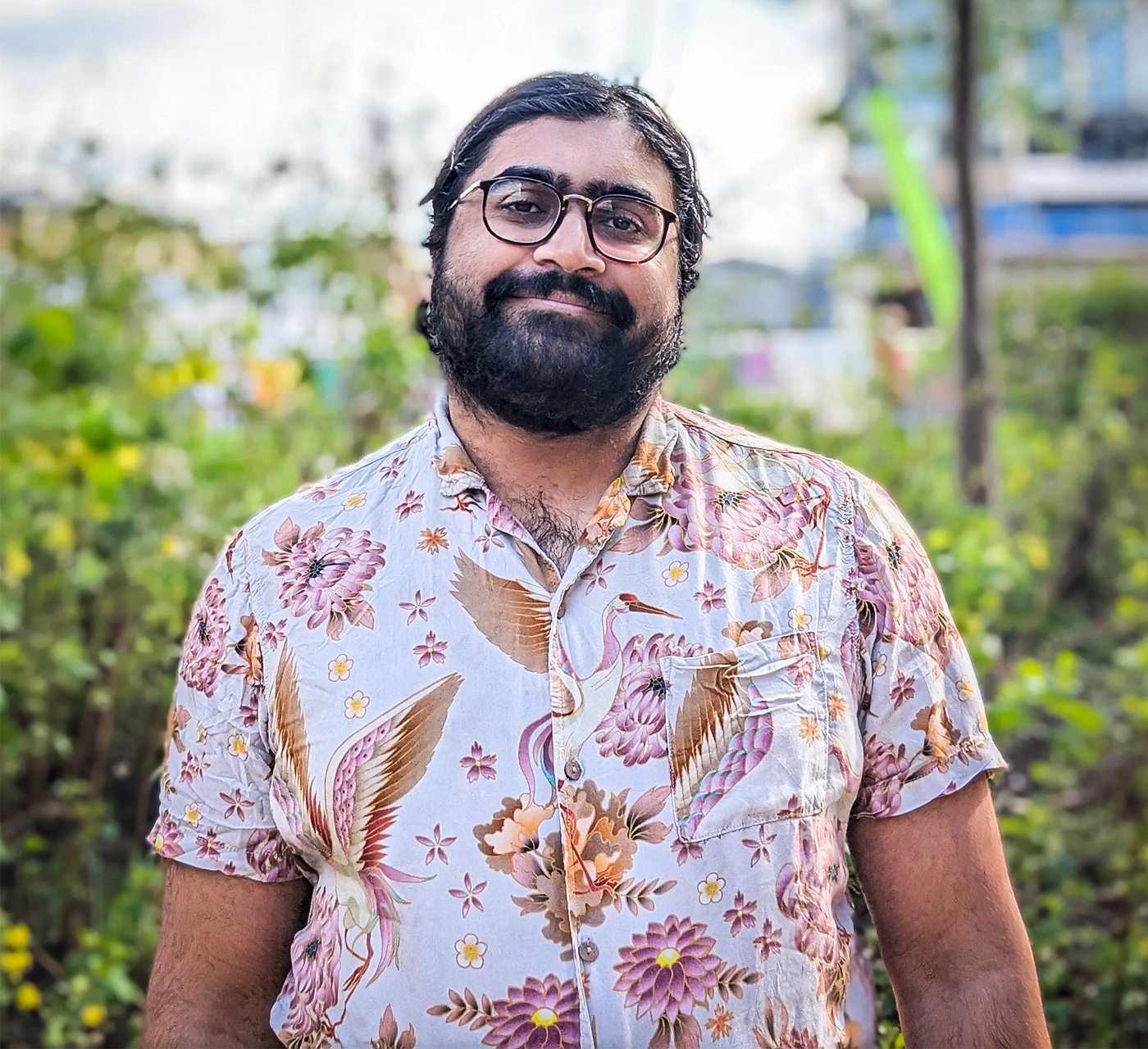 Neel Nanda in a print shirt stands outside.